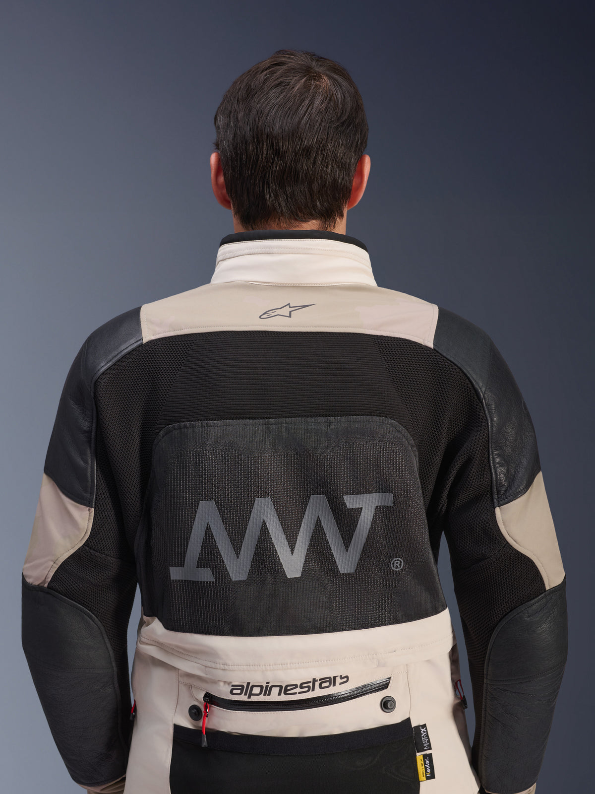 Achteraanzicht van de Alpinestars AMT-10LAB Drystar® XF Jacket in White Sand en Black, met een groot AMT-logo op het mesh rugpaneel, Alpinestars-branding op de onderrug en technische textielconstructie voor adventure motorrijden