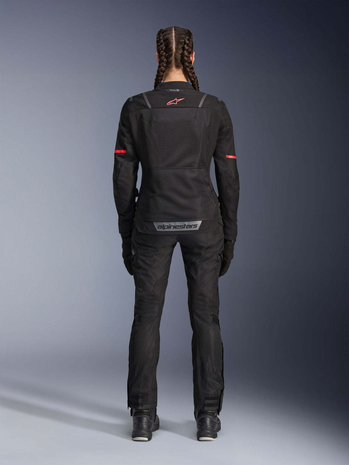 Alpinestars Stella Andes Air Drystar® Broek, dames motorbroek, zwart, achteraanzicht gedragen met een bijpassende mesh jas met rode accenten, met mesh ventilatiepanelen en reflecterende branding op de onderrug, ontworpen voor adventure en road touring.