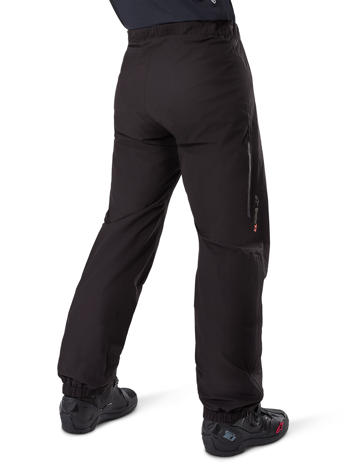 Alpinestars Amt-8 Stretch Drystar® XF broekvoering, zwart, achteraanzicht van de waterdichte voering gedragen over zwarte motorlaarzen, voorzien van Drystar XF-branding op het onderbeen, elastische enkelboorden en lichtgewicht stretchmateriaal voor adventure-touring.