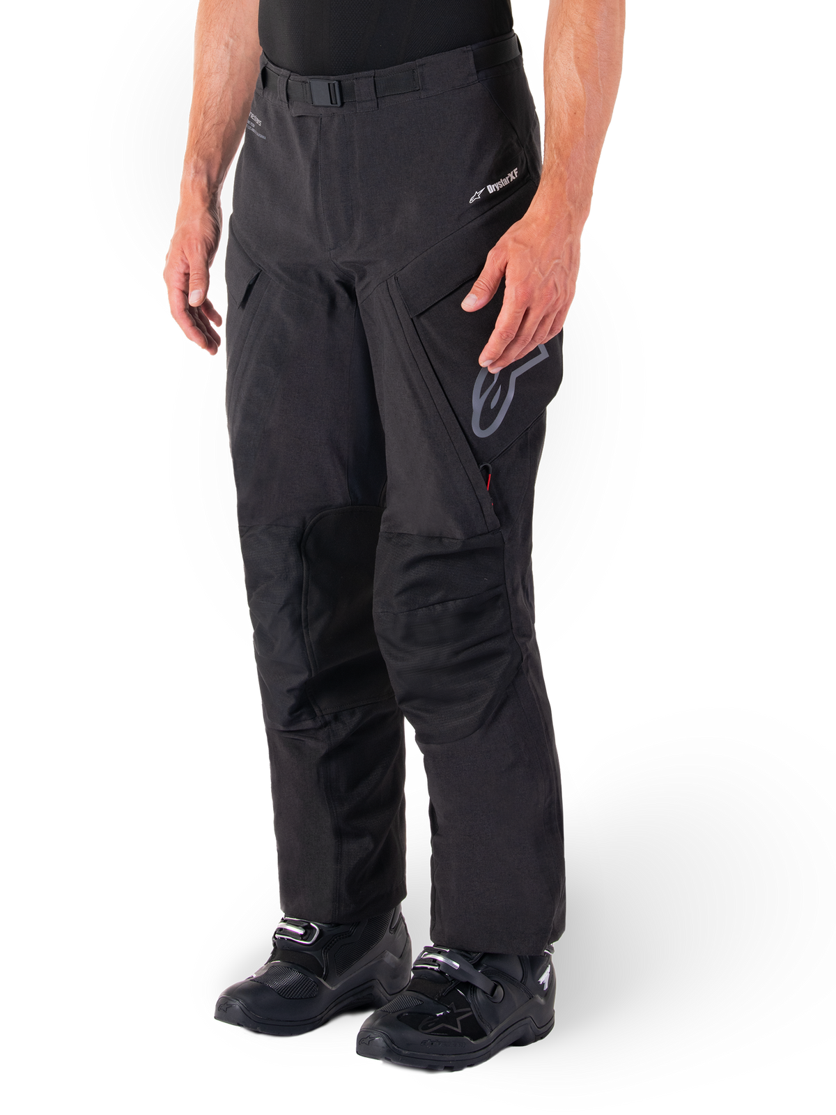 Alpinestars Hyde XT Drystar® broek, adventure touring motorbroek, zwart, gedragen met zwarte laarzen, voorzien van gelamineerde Drystar®XF membraan-branding, versterkte kniepanelen en cargozakken met ritssluiting.