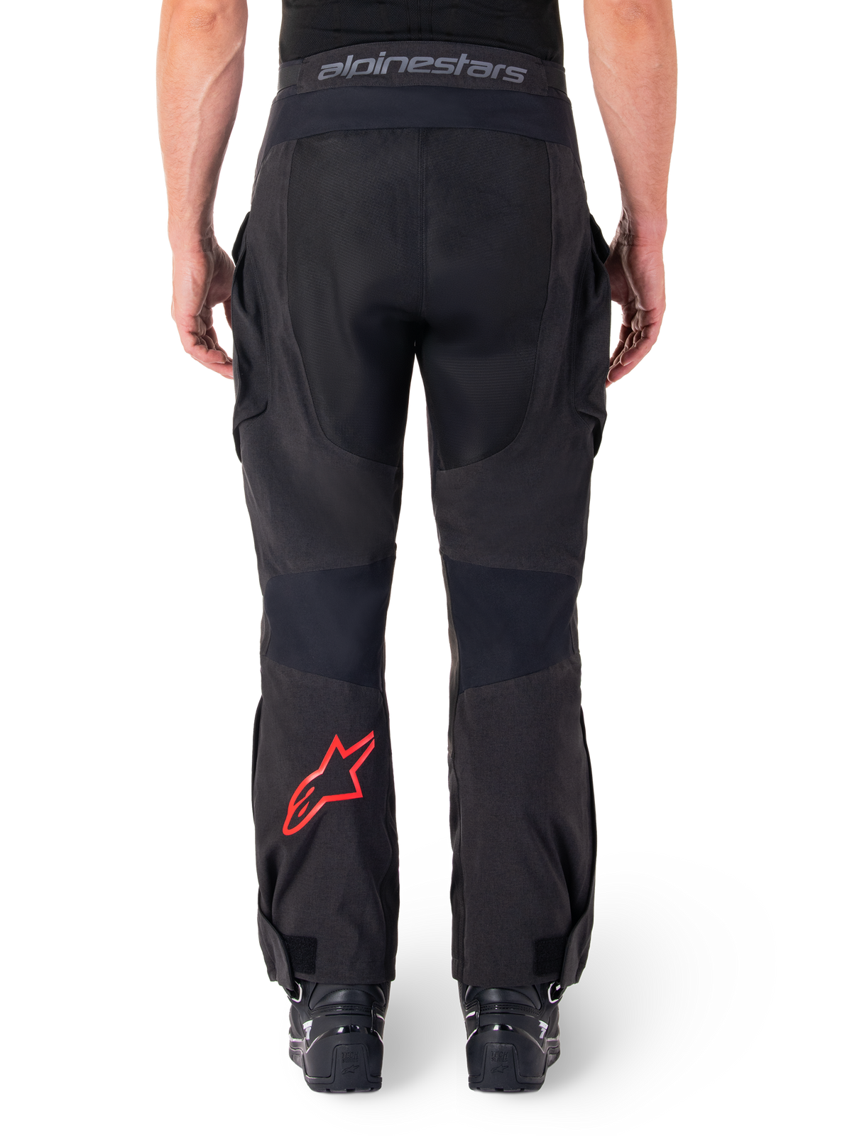 Alpinestars Hyde XT Drystar® broek, adventure motorbroek, zwart met rood sterlogo op het onderbeen, achteraanzicht, over-de-laars enduro-ontwerp met duurzame textielpanelen en tailleband met merklogo.