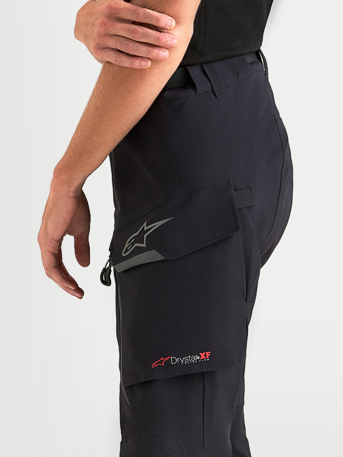 Alpinestars Maxdura Drystar XF Laminated broek, avontuurlijke motorbroek voor heren in zwart en donkergrijs, met een waterbestendige cargozak met reflecterend Astar-logo en Drystar XF-branding, detailopname van zijkant
