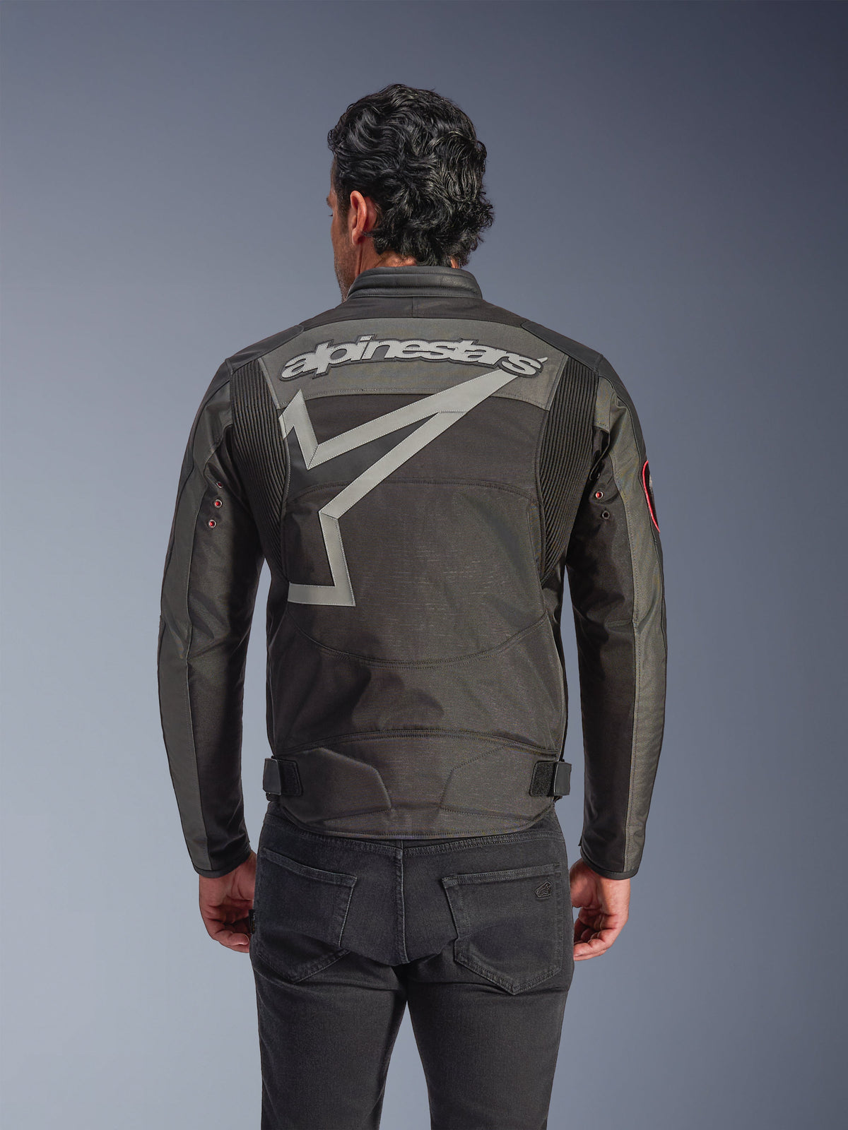 Alpinestars Axton Jacket, motorjas voor heren, Black Anthracite Red Tangerine, achteraanzicht met een groot grijs Alpinestars-woordmerk en gestileerde ster-graphic, accordeon schouderpanelen en vintage-geïnspireerde metalen oogjes op de mouwen