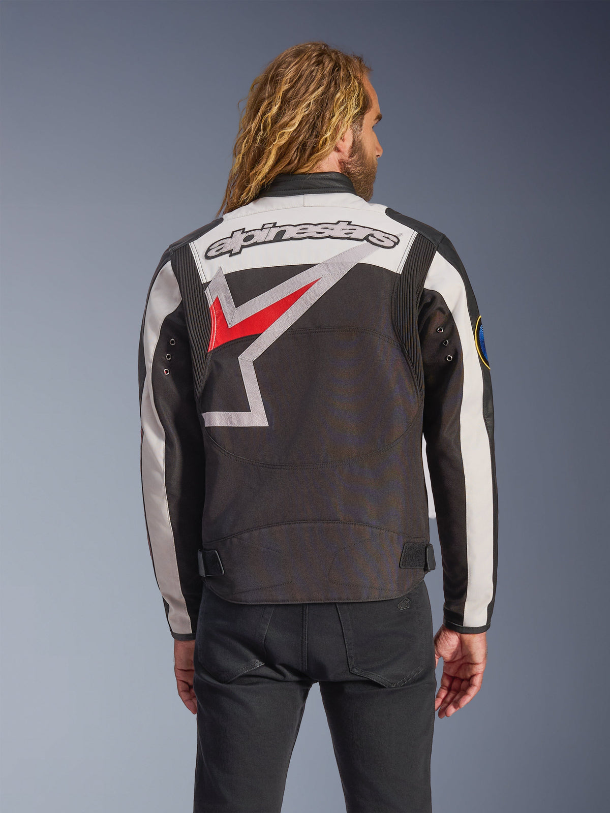 Alpinestars Axton Jas, motorjas, zwart, gebroken wit en felrood, achteraanzicht met een groot rondom doorlopend sterlogo en woordmerk, vintage racing-geïnspireerd ontwerp met accordeon schouderpanelen en tailleverstellers