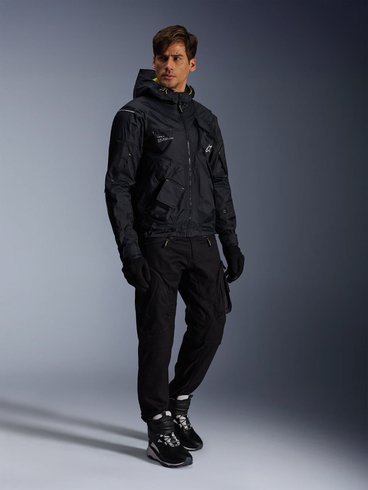 Alpinestars Mogress Air-jas, urban motorjas, zwart met Lime Punch en witte accenten, gedragen met zwarte motorbroek, handschoenen en zwart-witte laarzen, eigentijds utility-geïnspireerd ontwerp.