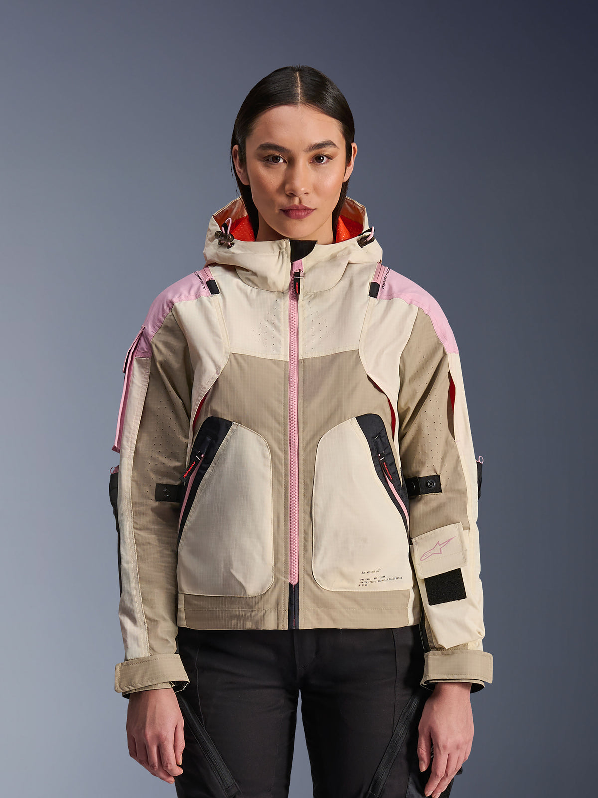 Alpinestars Molly Air Jacket, urban motorjas voor dames, kleurstelling Sand Pink Almond, ontwerp met capuchon en laser-geperforeerde ventilatie, roze ritsdetail, verstelbare mouwbanden, getoond op een model.