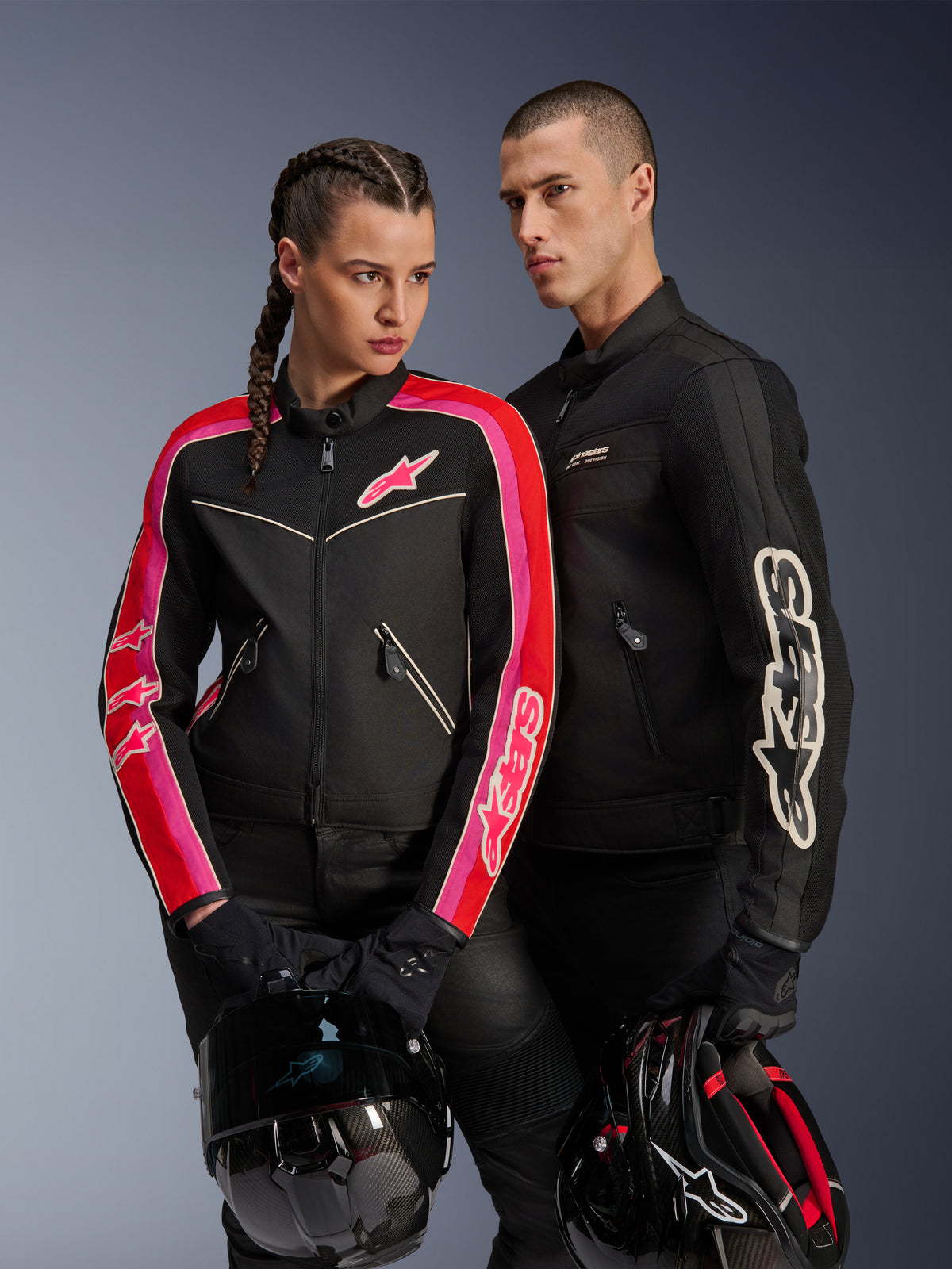 Alpinestars Stella T-Dyno Air damesjas in Black Bright Red Fuchsia, gecombineerd met de zwarte Dyno Air herenjas, beide motorrijders houden motorhelmen vast, studiofoto van moderne urban motorkleding