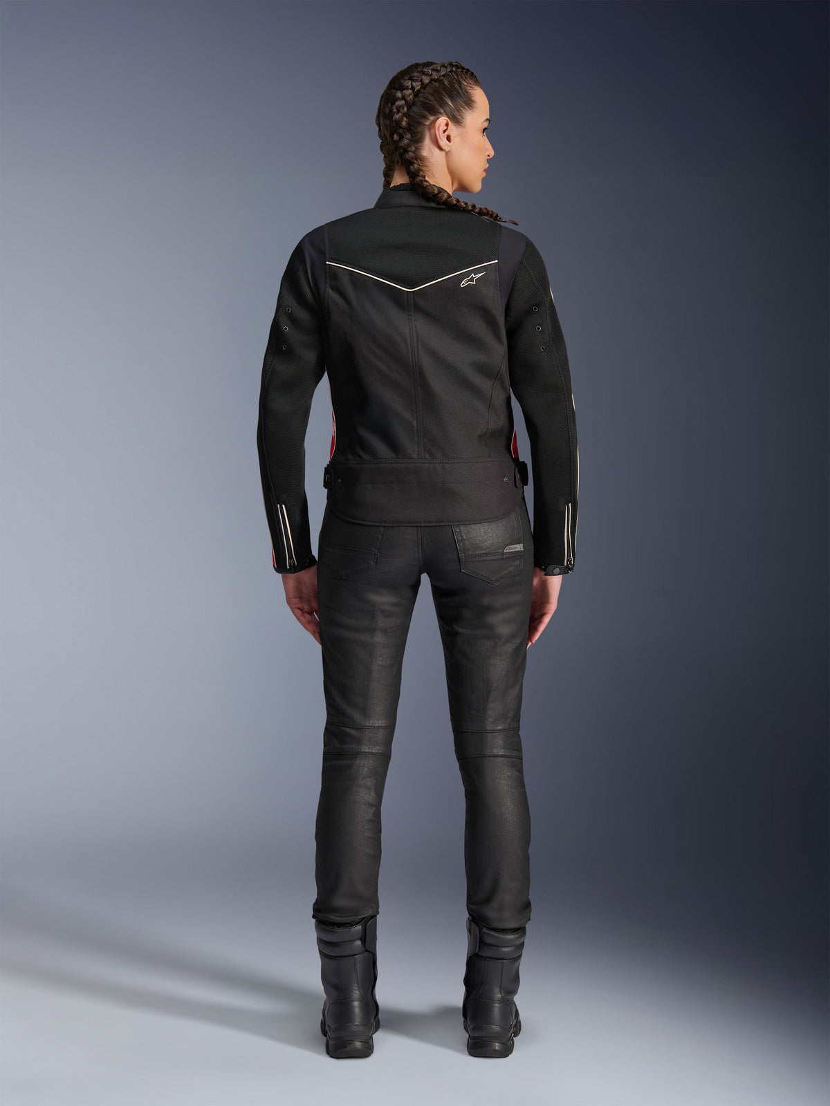 Alpinestars Stella T-Dyno Air Jas, achteraanzicht, zwarte dames motorjas met witte biezen en een klein sterlogo, gedragen met een zwarte technische broek en motorlaarzen, slanke biker-pasvorm voor urban rijden op de weg