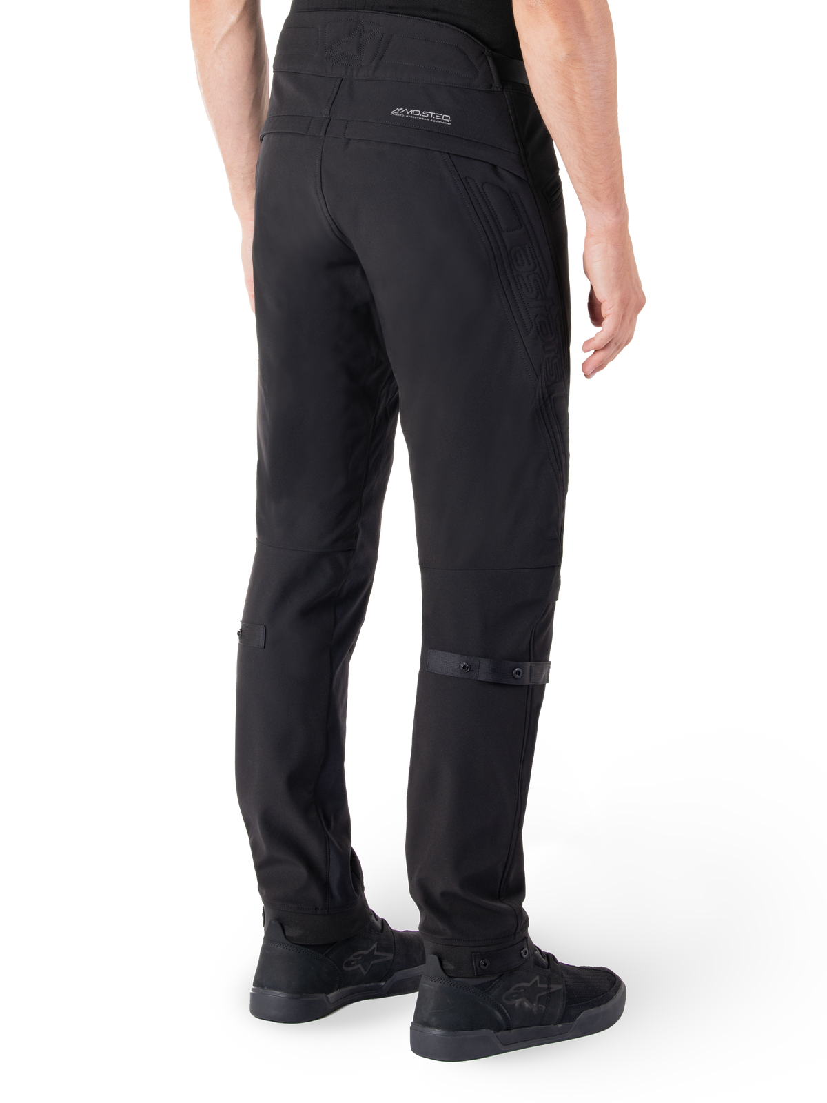 Alpinestars Alden broek, urban motorbroek, zwart, achteraanzicht met technische softshell stof en gewatteerde details, MO.ST.EQ. reflecterende branding op de achterpas en verstelbare kuitbanden, gecombineerd met zwarte motorschoenen