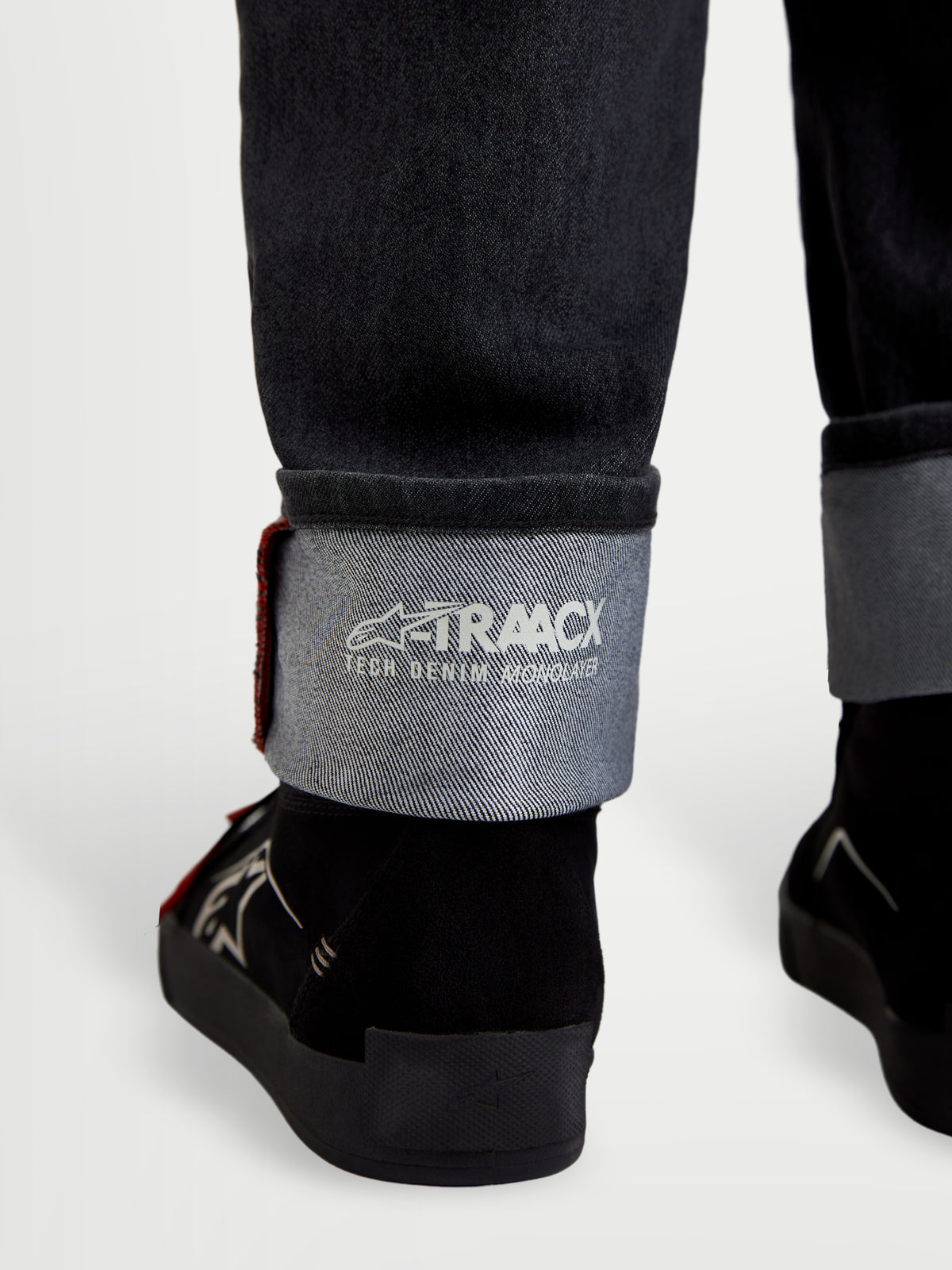 Alpinestars Flex Ast 7 Denim Broek, motorjeans in vervaagd zwart, close-up van omgeslagen zoom met A-TRAACX technische denimbranding en zelfkantdetails