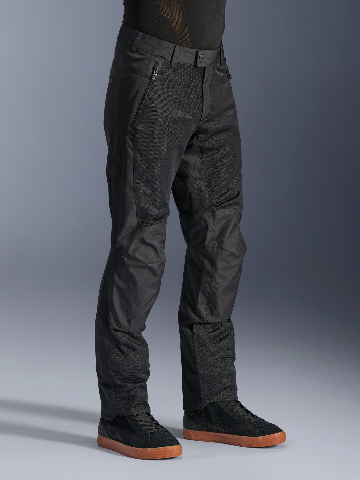 Alpinestars C-1 Air broek, urban motorbroek, zwart, voorzien van ademende tech mesh-panelen en polyfabric constructie, gedragen met zwarte sneakers, strak en functioneel ontwerp voor stadsritten.