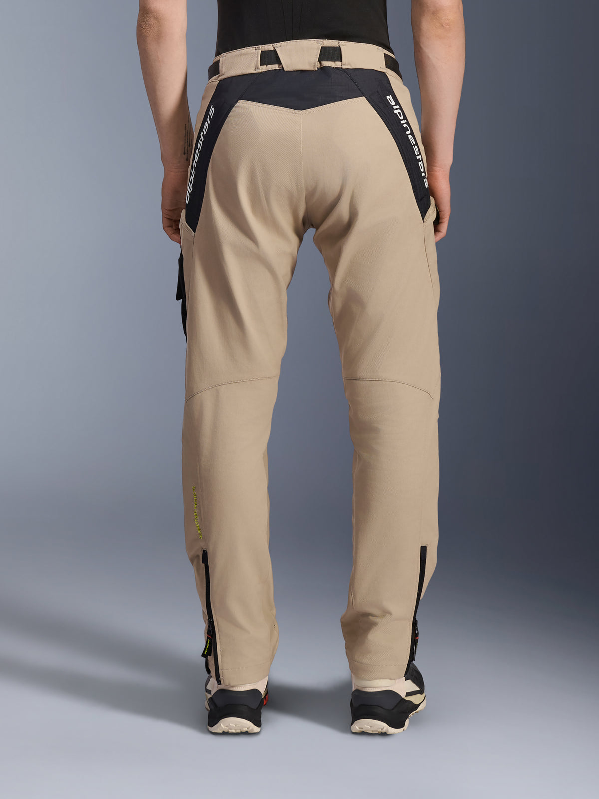 Alpinestars Acteon broek, urban motorbroek, sand, achteraanzicht met zwarte ripstop-panelen en witte merkaanduiding op de pas, taps toelopende pasvorm met ritsen onderaan de broekspijpen, eigentijdse motorkleding voor op de weg