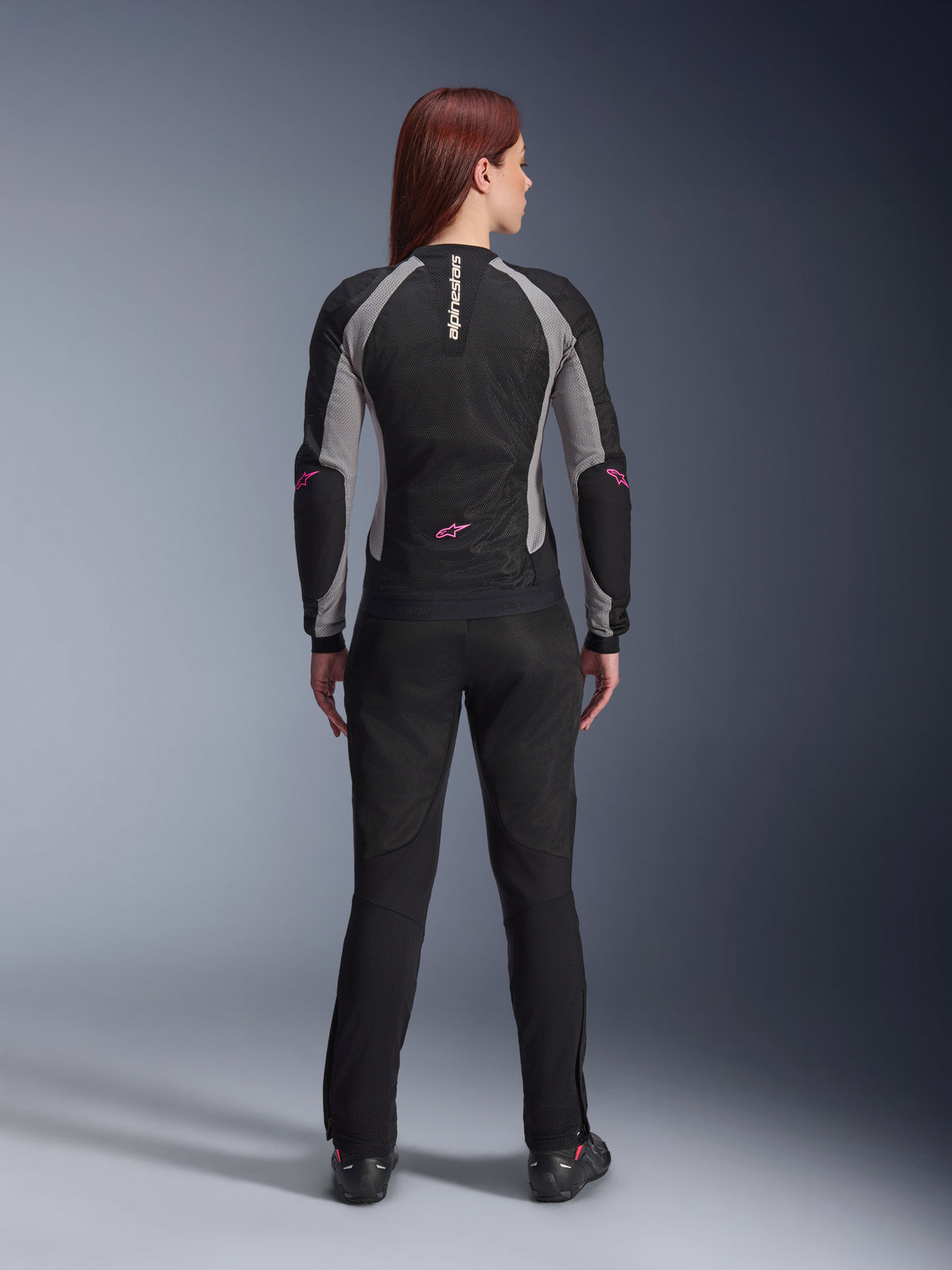 Alpinestars Stella Troop-Air damesbroek in het zwart, achteraanzicht, gecombineerd met een zwart en grijs mesh motorjack met roze accenten, studio-opname die het technisch geventileerde textielontwerp laat zien