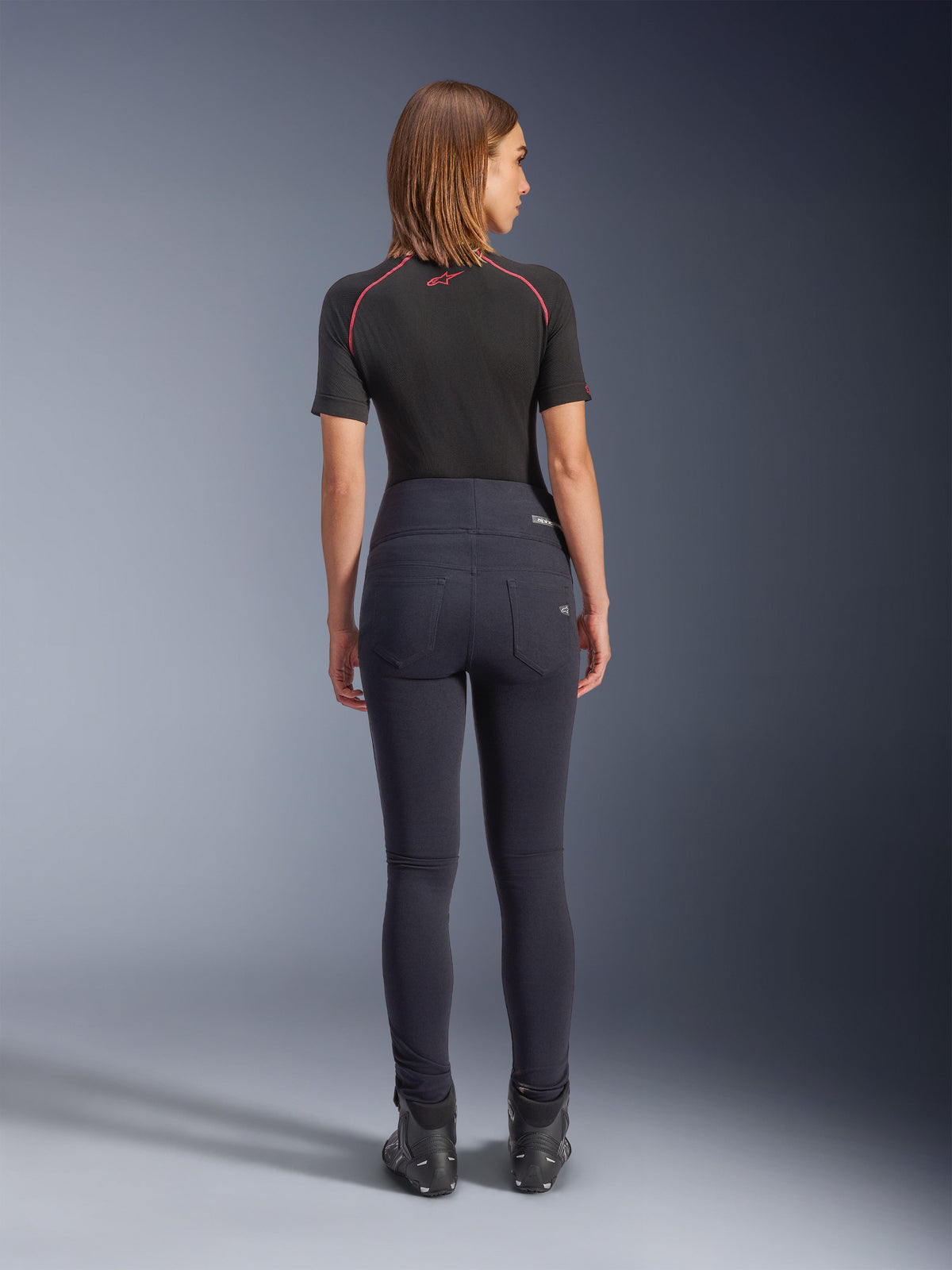 Alpinestars Stella Flex-AST Leggings in het zwart, hooggetailleerde dames motorbroek, achteraanzicht met skinny pasvorm en achterzakken, gedragen met zwart shirt met korte mouwen en motorlaarzen, urban motorkleding