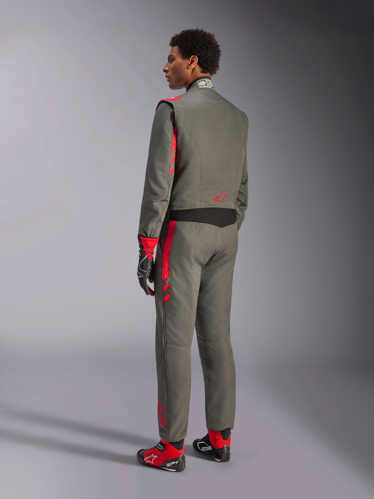 Alpinestars GP Race V3 Suit FIA, Anthracite Red racing suit, back view of model wearing the two-layer suit, red accents on shoulders and legs, paired with matching gloves and boots, professional auto racing gear