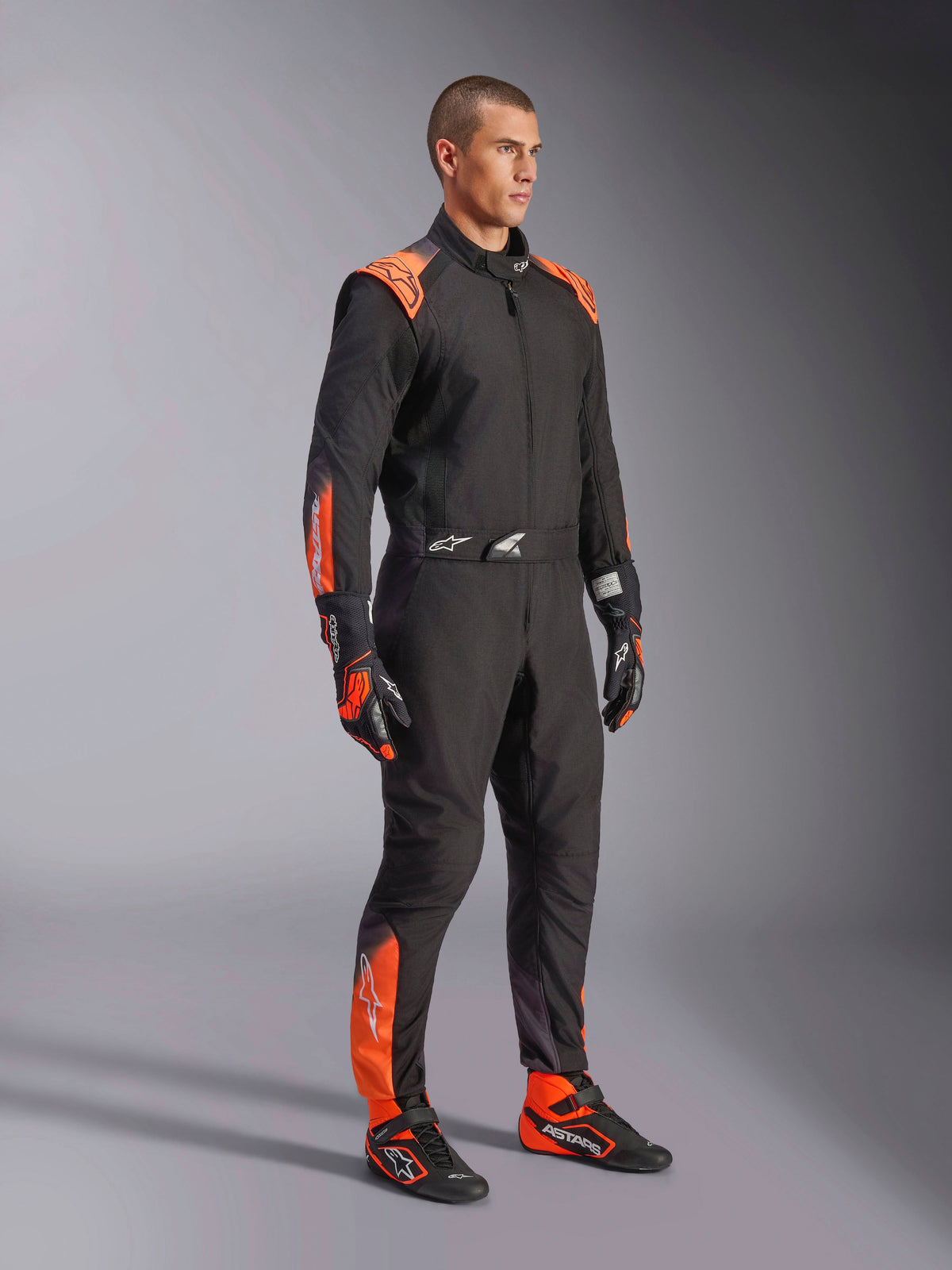 Alpinestars KMX-5 V3 pak, heren kartpak in zwart en oranje fluo, FIA Grade 1 textiel, gedragen door een model.