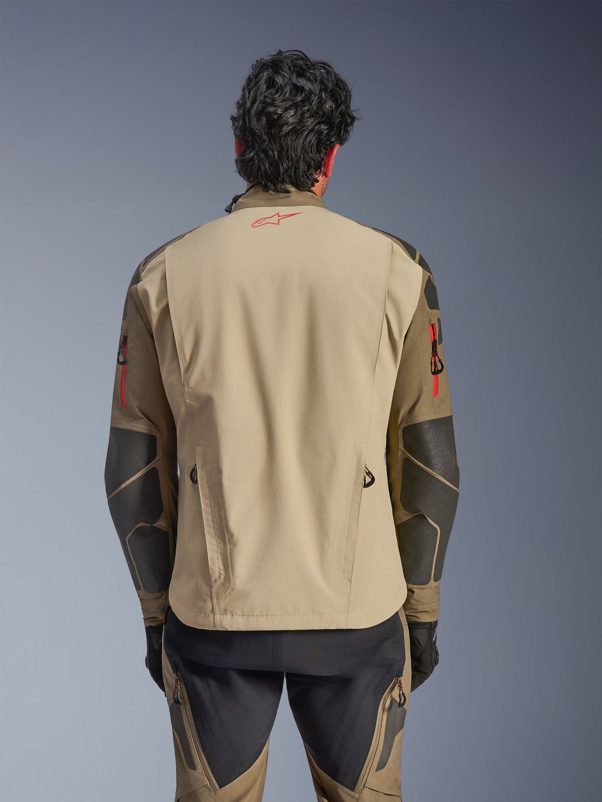 Alpinestars Nazca 3L GORE-TEX PRO Jas, achteraanzicht, Walnut Rock Brown, avontuurlijke motorjas met rood Astars-logo in de nek en rode ritsaccenten op de armen, voorzien van Superfabric-verstevigingen op de ellebogen.