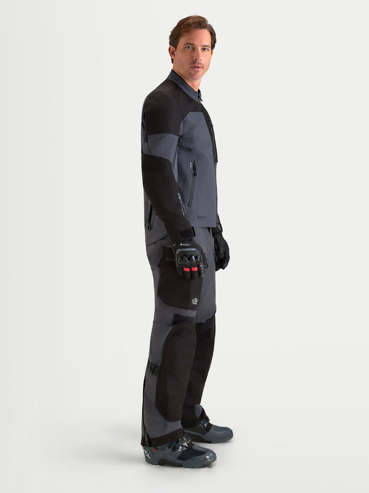 Alpinestars Arenis Gore-Tex Gear Set, men's adventure touring motorcycle jacket and pants in black and deep gray, side profile view on a model wearing matching adventure gear, waterproof GORE-TEX textile construction.