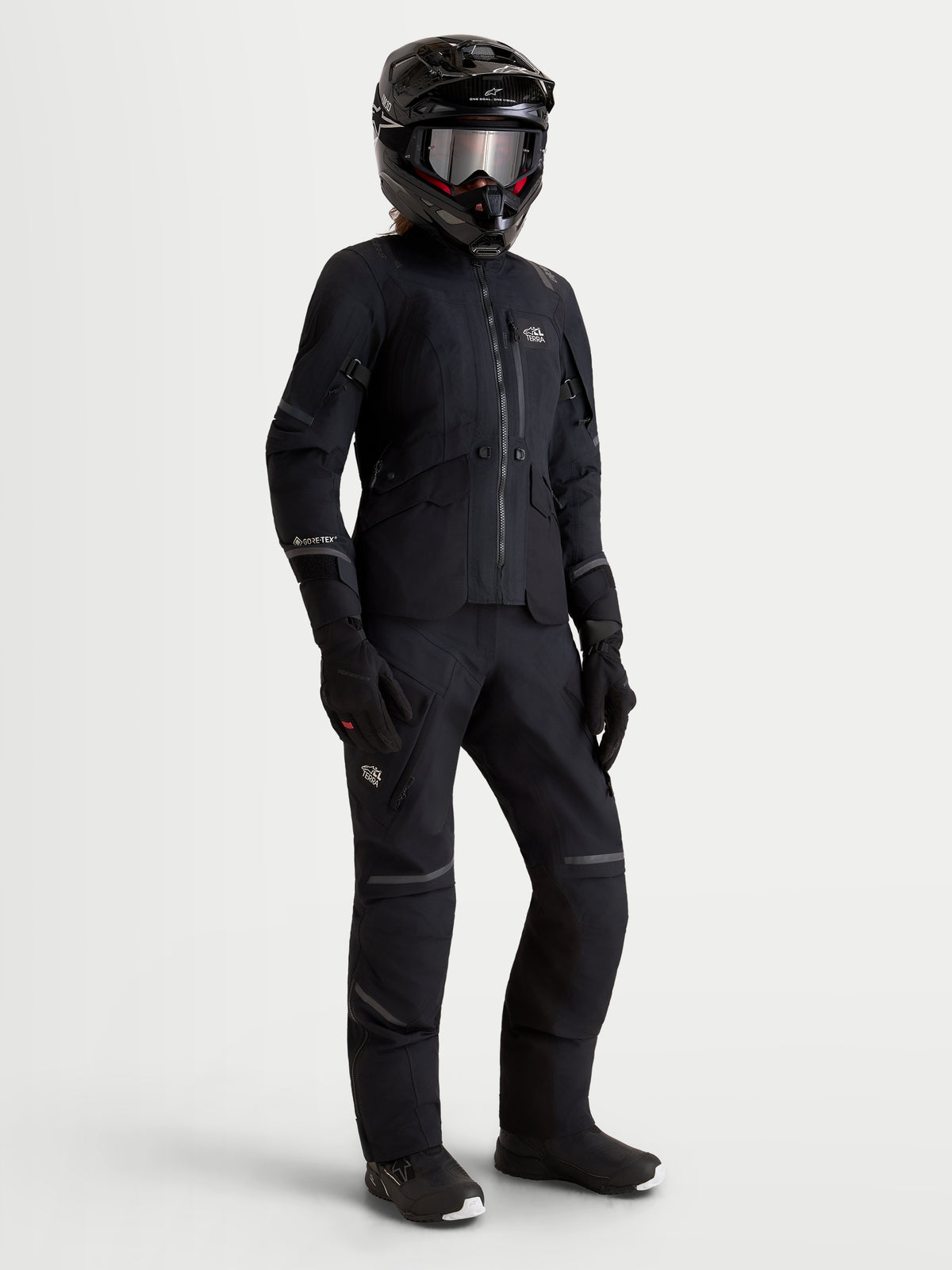 Alpinestars Stella St-7 V2 2L Gore-Tex jas en Stella St-7 V2 2L Gore-Tex broek, dames adventure-motoruitrusting in het zwart, vooraanzicht op model met volledige rijuitrusting inclusief helm en handschoenen