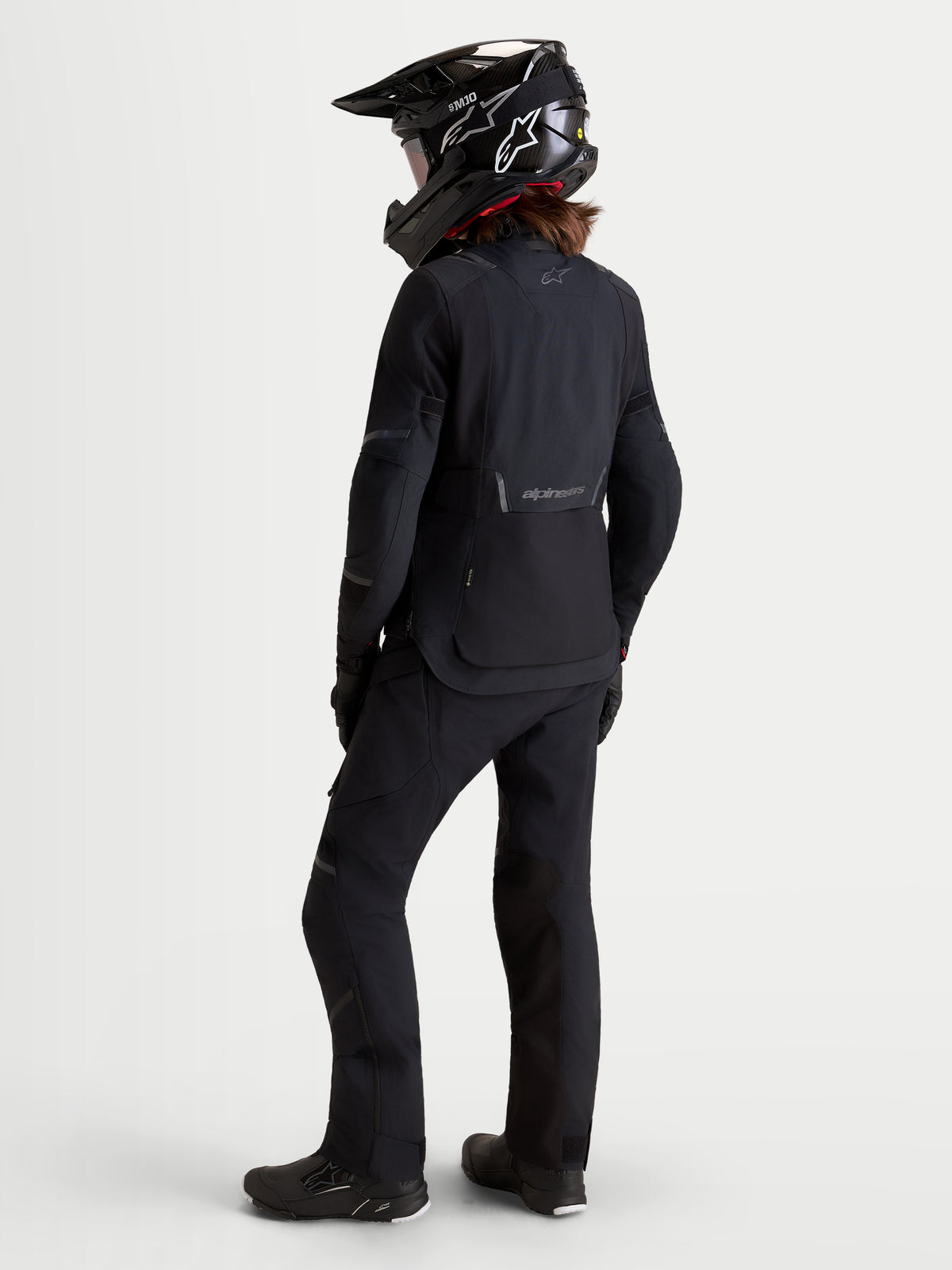 Alpinestars Stella ST-7 V2 2L GORE-TEX jas, dames adventure motorjas in zwart, achteraanzicht op model met bijpassende uitrusting en helm, waterdichte textielconstructie