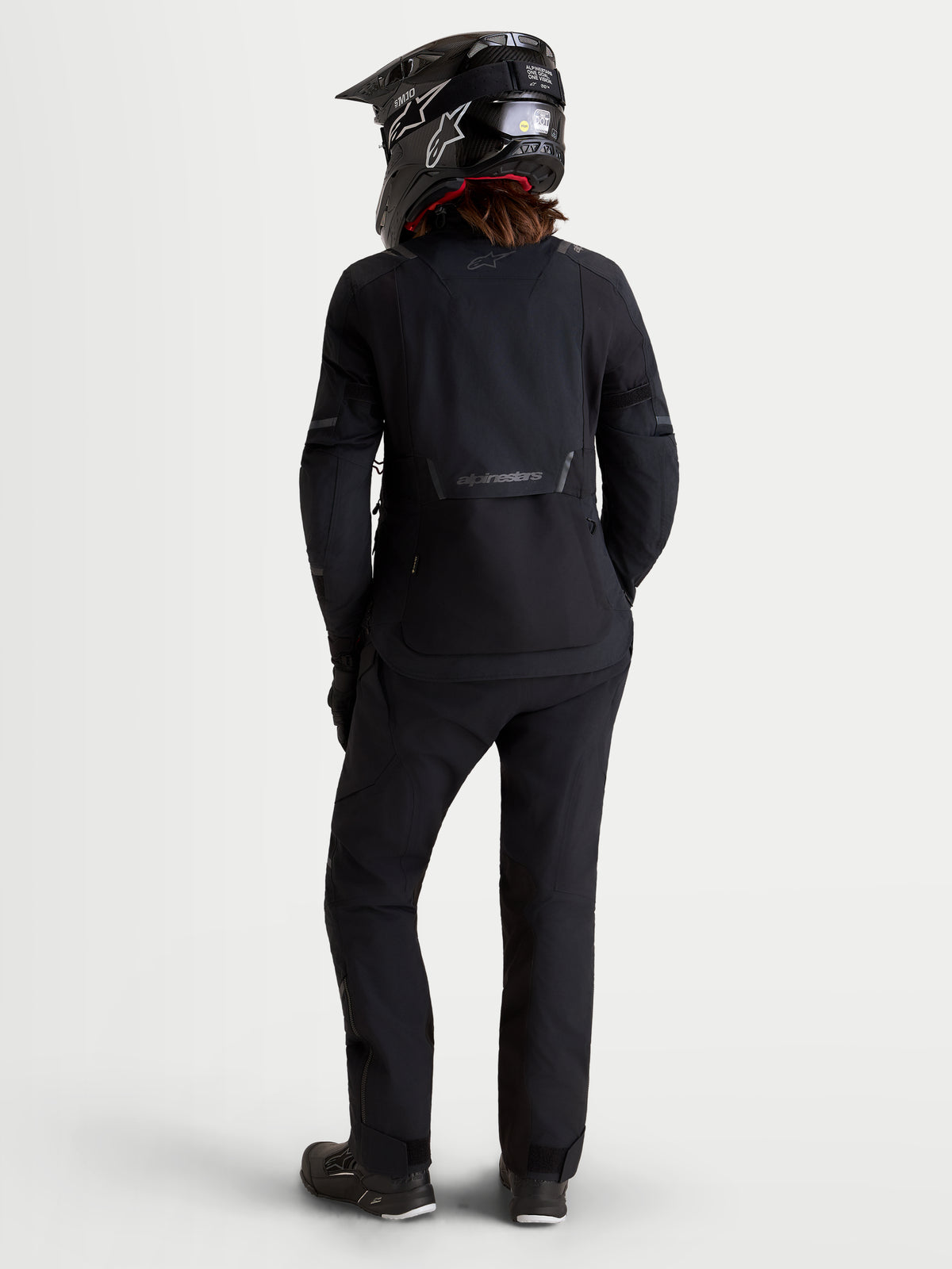 Alpinestars Stella ST-7 V2 2L GORE-TEX jas, dames adventure motorjas in zwart, achteraanzicht op een model met bijpassende uitrusting en helm, waterdichte textielconstructie
