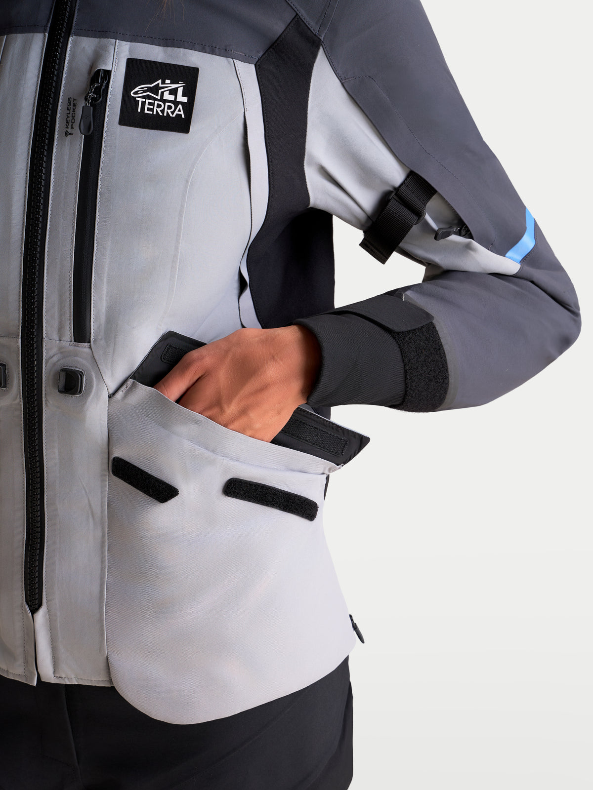 Alpinestars Stella ST-7 V2 2L Gore-Tex® Jacket, women's adventure touring motorcycle jacket in mid gray, deep gray, and black, close-up view showing waterproof cargo pocket and All Terra patch.