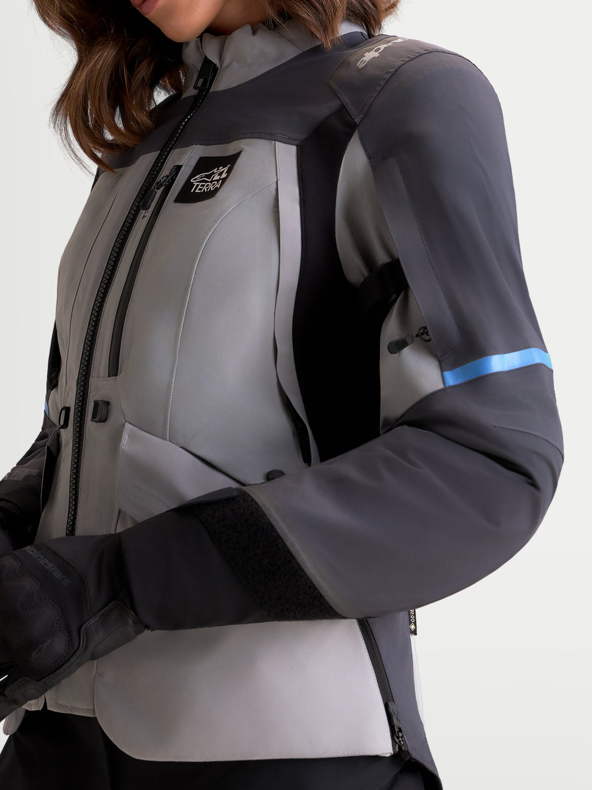 Alpinestars Stella St-7 V2 2L Gore-Tex® Jacket, women's adventure touring motorcycle jacket in mid gray, deep gray, and black, close-up view showing waterproof textile construction, zippered ventilation, and ergonomic collar worn by a model.