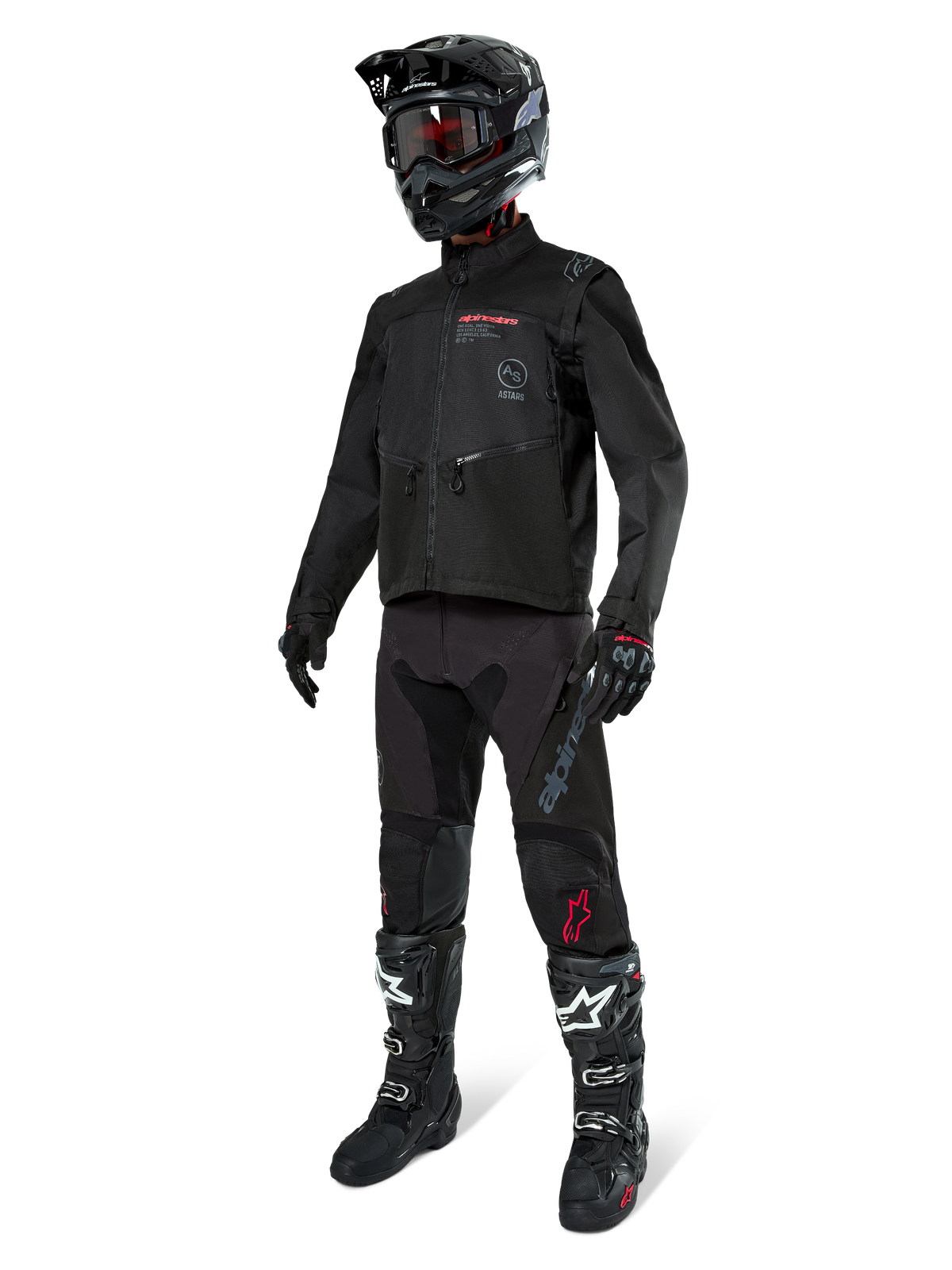 Alpinestars Pro-Dura Jas in het zwart, motorcrossrijder in volledige race-uitrusting, zwarte broek met grijze branding en rode accenten, zwarte helm met crossbril, zwart-witte motorcrosslaarzen, gecoördineerde outfit voor enduro en off-road rijden