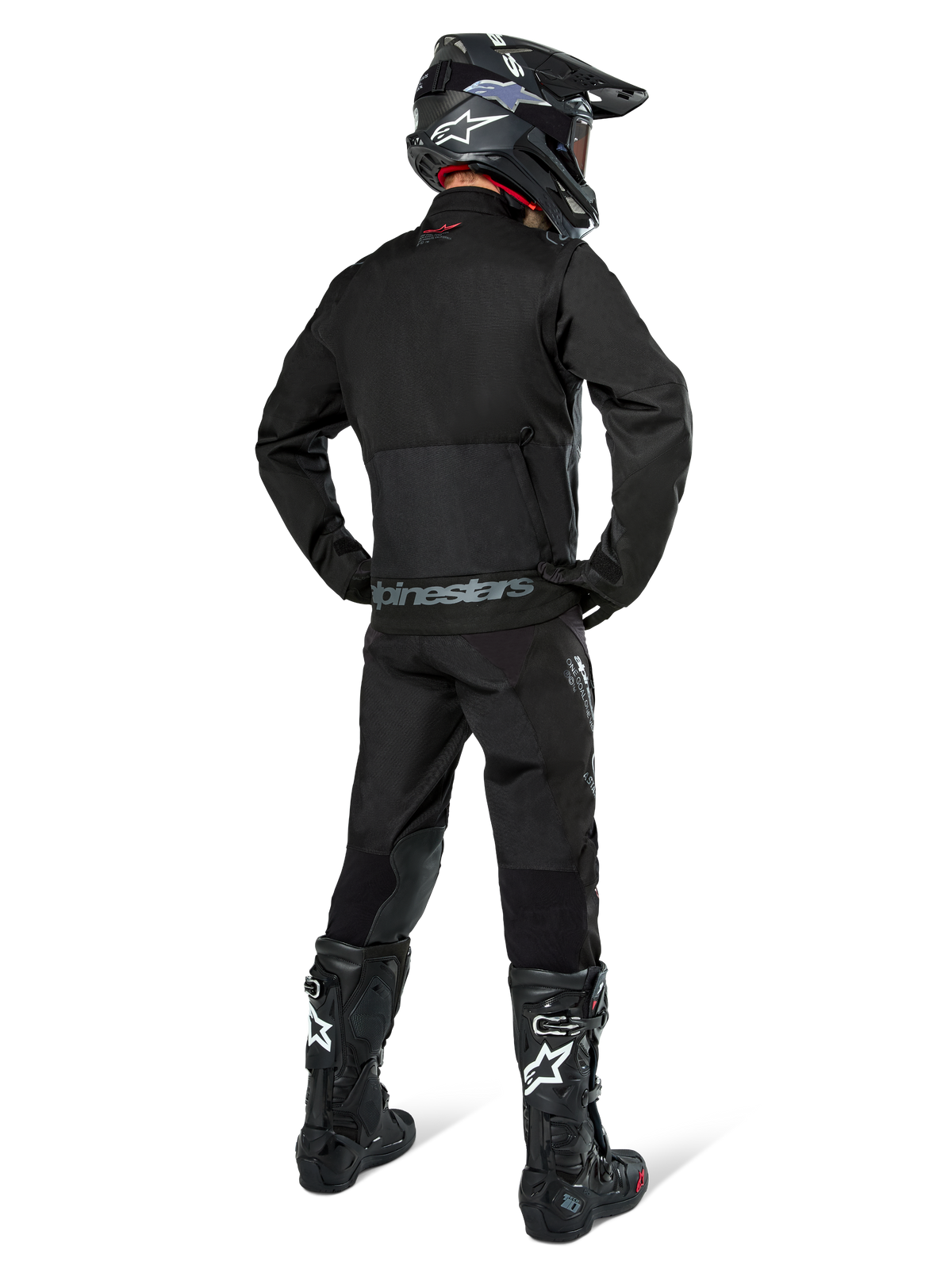 Alpinestars Pro-Dura Jas, zwarte off-road enduro jas, achteraanzicht gedragen met bijpassende broek en zwarte Tech 10 laarzen, met opvallende Alpinestars-branding op de onderrug, robuuste textielconstructie voor agressief trailrijden.