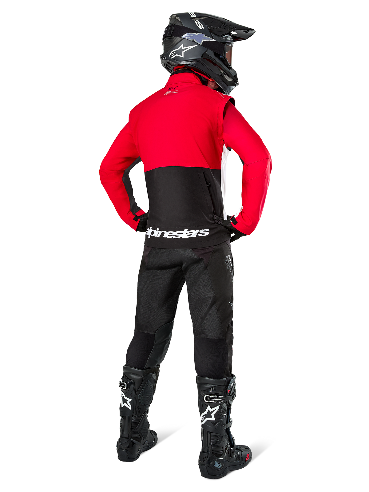 Motocrossrijder van achteren gezien, dragend de Alpinestars Pro-Dura jas in zwart, felrood en wit, gecombineerd met een zwarte broek, zwarte helm en zwarte off-road laarzen, met een rood bovenstuk en een zwart onderstuk met witte Alpinestars-logo's op de rug.
