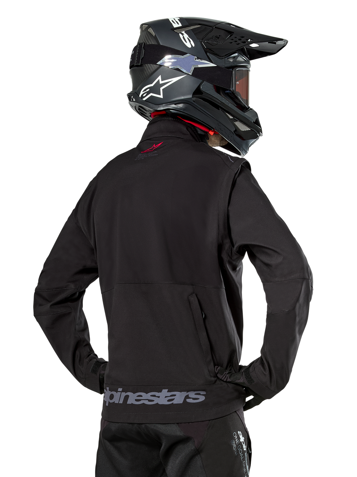 Alpinestars Lite-Dura Softshell Jacket, Black, back view worn by a rider, featuring gray Alpinestars branding on the rear hem and a small red logo on the collar, paired with a black motocross helmet, designed for enduro and off-road riding.