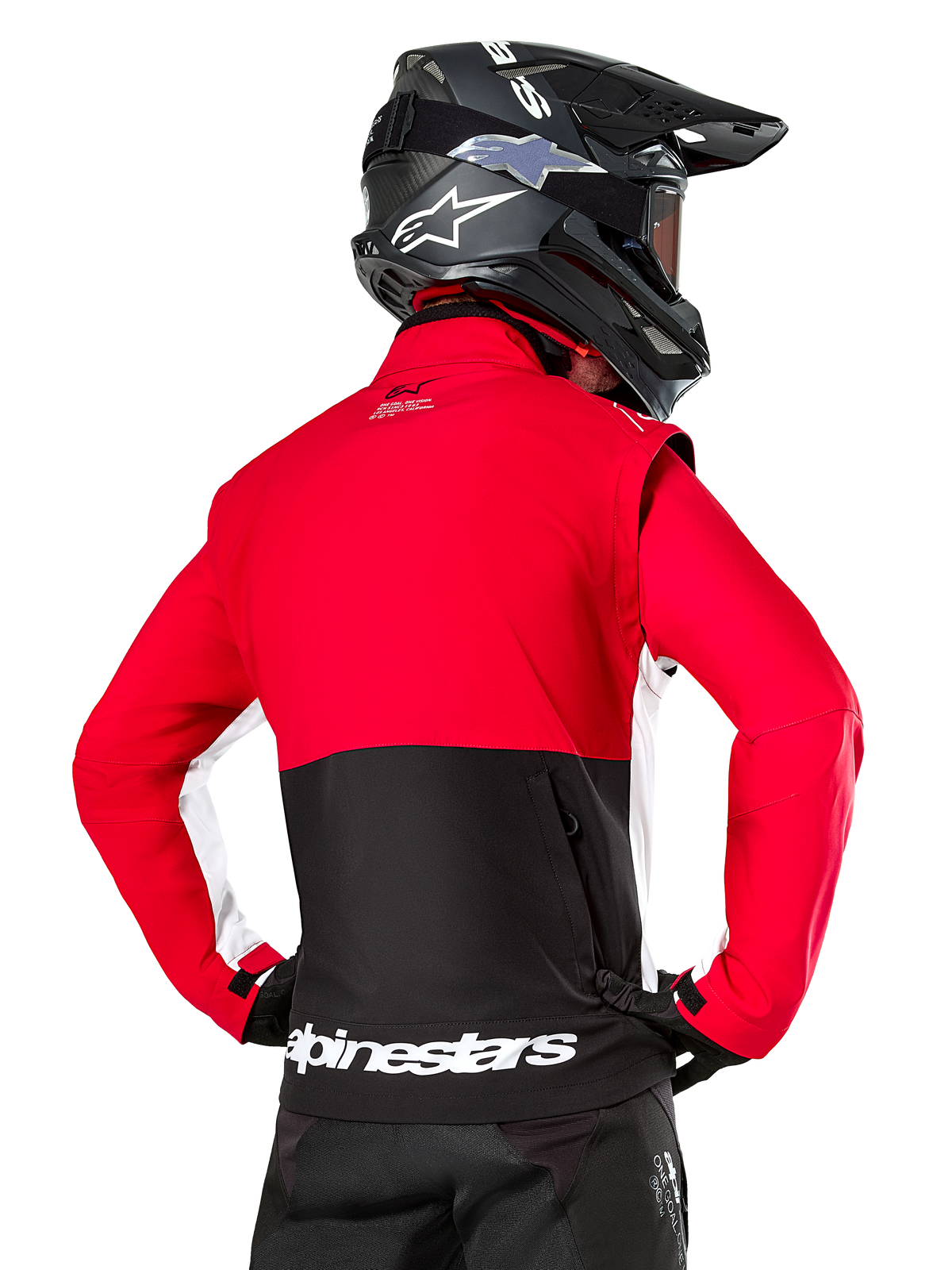 Alpinestars Lite-Dura Softshell Jacket, Black Bright Red White, achteraanzicht op een motorcrosser, rood bovenstuk en mouwen met een zwart paneel op de onderrug, opbergzak met rits op de rug, wit Alpinestars-logo op de onderste zoom, gedragen met een zwarte helm en broek