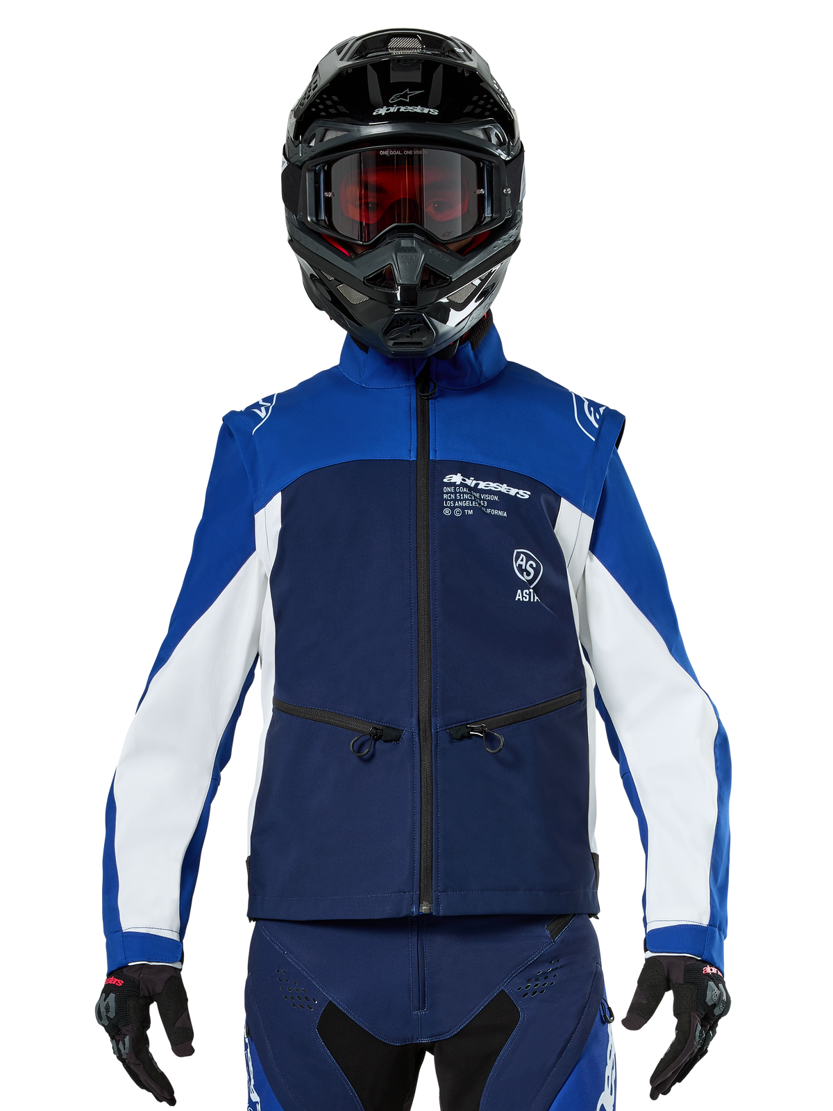 Motocross-rijder met de Alpinestars Lite-Dura Softshell Jas in Navy Bright Blue White, vooraanzicht, gecombineerd met een zwarte helm en een bril met rode glazen, voorzien van een technisch winddicht ontwerp met ritszakken en witte accenten voor off-road enduro rijden
