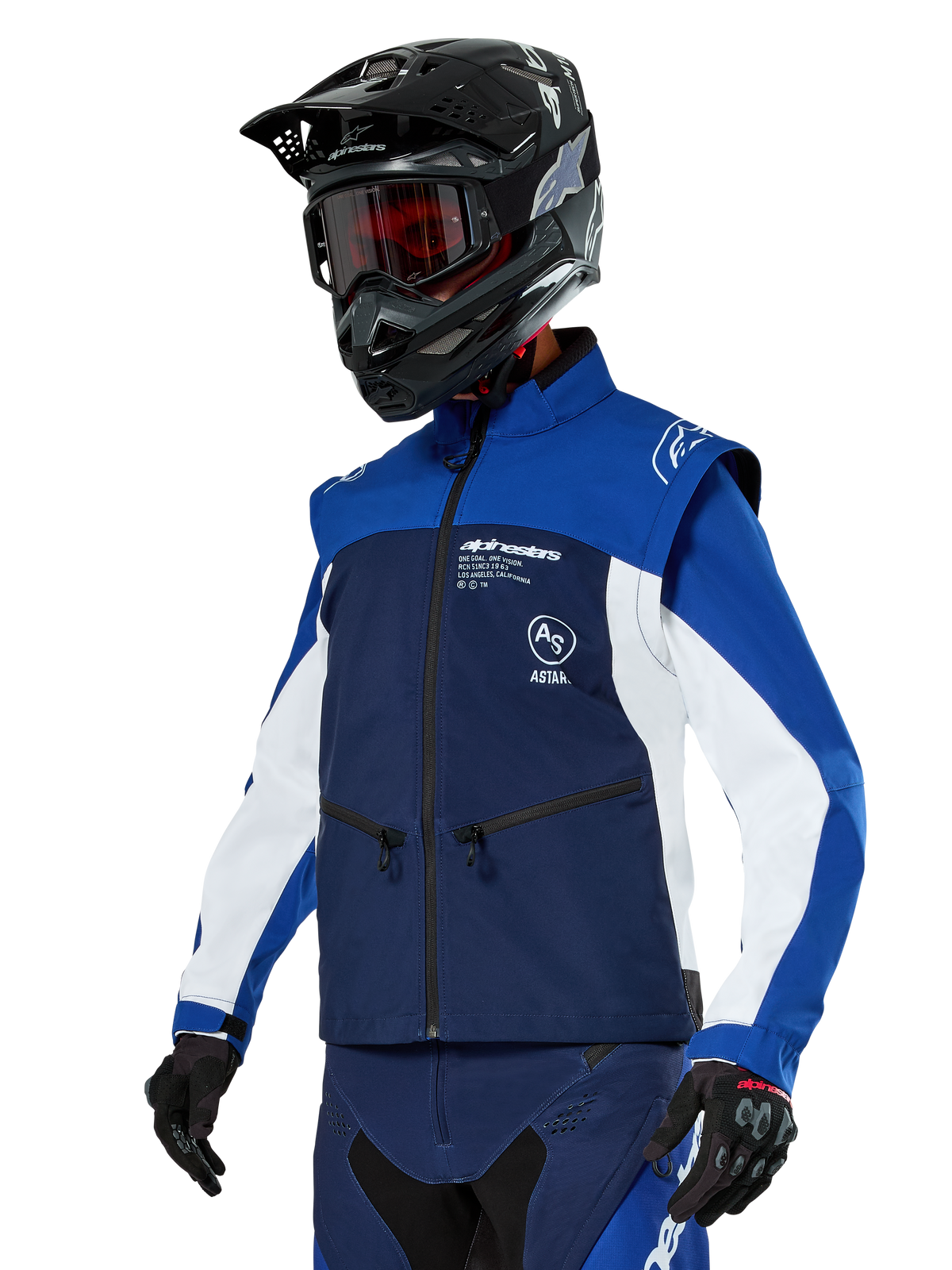 Alpinestars Lite-Dura Softshell Jacket, navy, felblauw en wit, off-road endurojas, gedragen met zwarte helm en rood getinte bril, sportief kleurblokontwerp met meerdere ritsen en merklogo's, duurzaam textiel voor motorcross en trailrijden