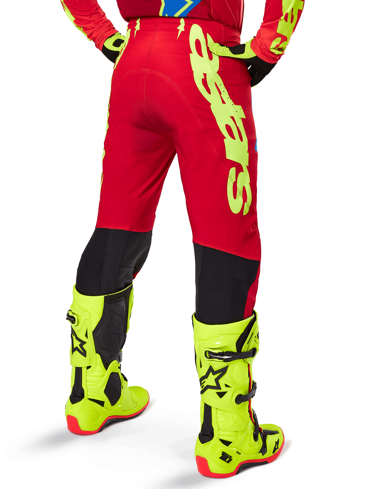 Alpinestars 2025 Supertech Maker broek, motorcrossbroek, helderrood en fluogeel, achteraanzicht met grote gele branding aan de zijkant en zwarte panelen op de onderbenen, gedragen met bijpassende fluogele laarzen en uitrusting