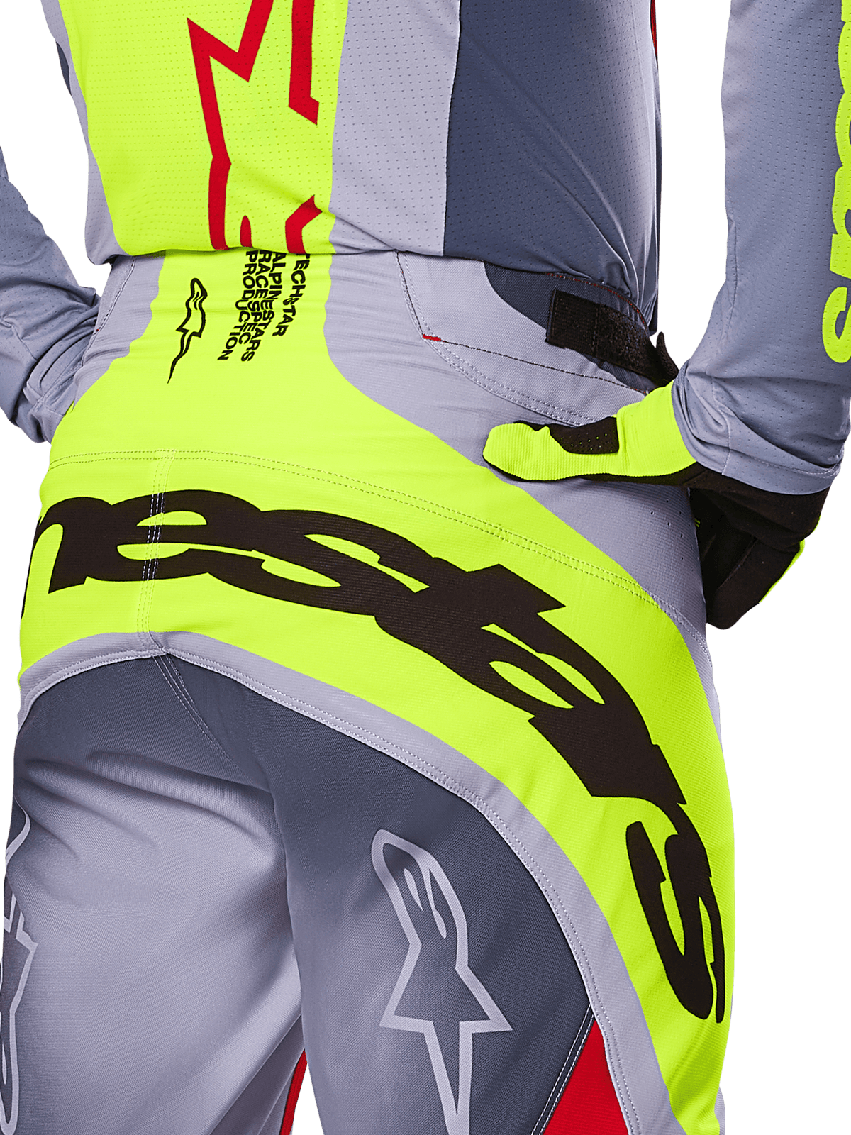 Alpinestars 2025 Techstar Melt crossbroek, close-up van het zitvlak en de taille, grijs en neongeel ontwerp met grote zwarte branding, voorzien van sterlogo's en race-spec tekst, hoogwaardige motorcrossuitrusting