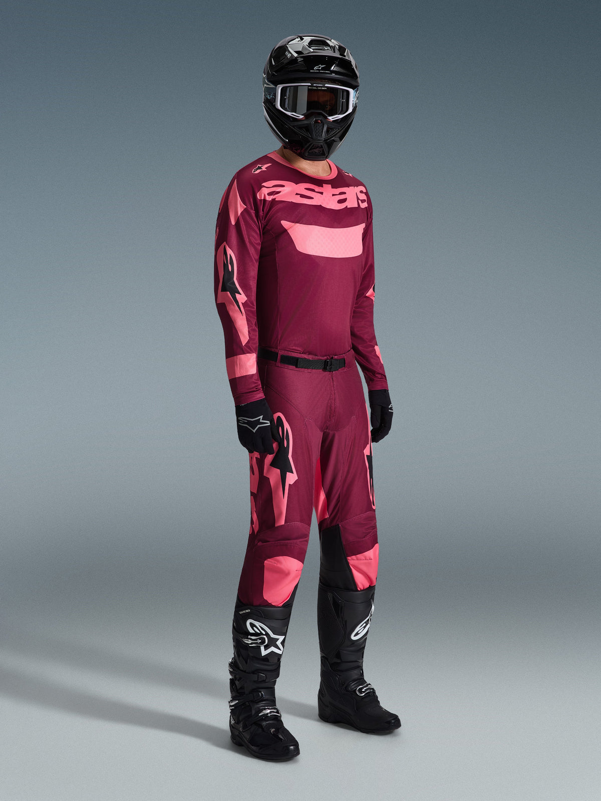 Alpinestars 2026 Racer Riway Gear Set, Motocross Jersey and Pants in Maroon and Pink, worn with a black helmet and black Tech series boots, full body view against a grey background.
