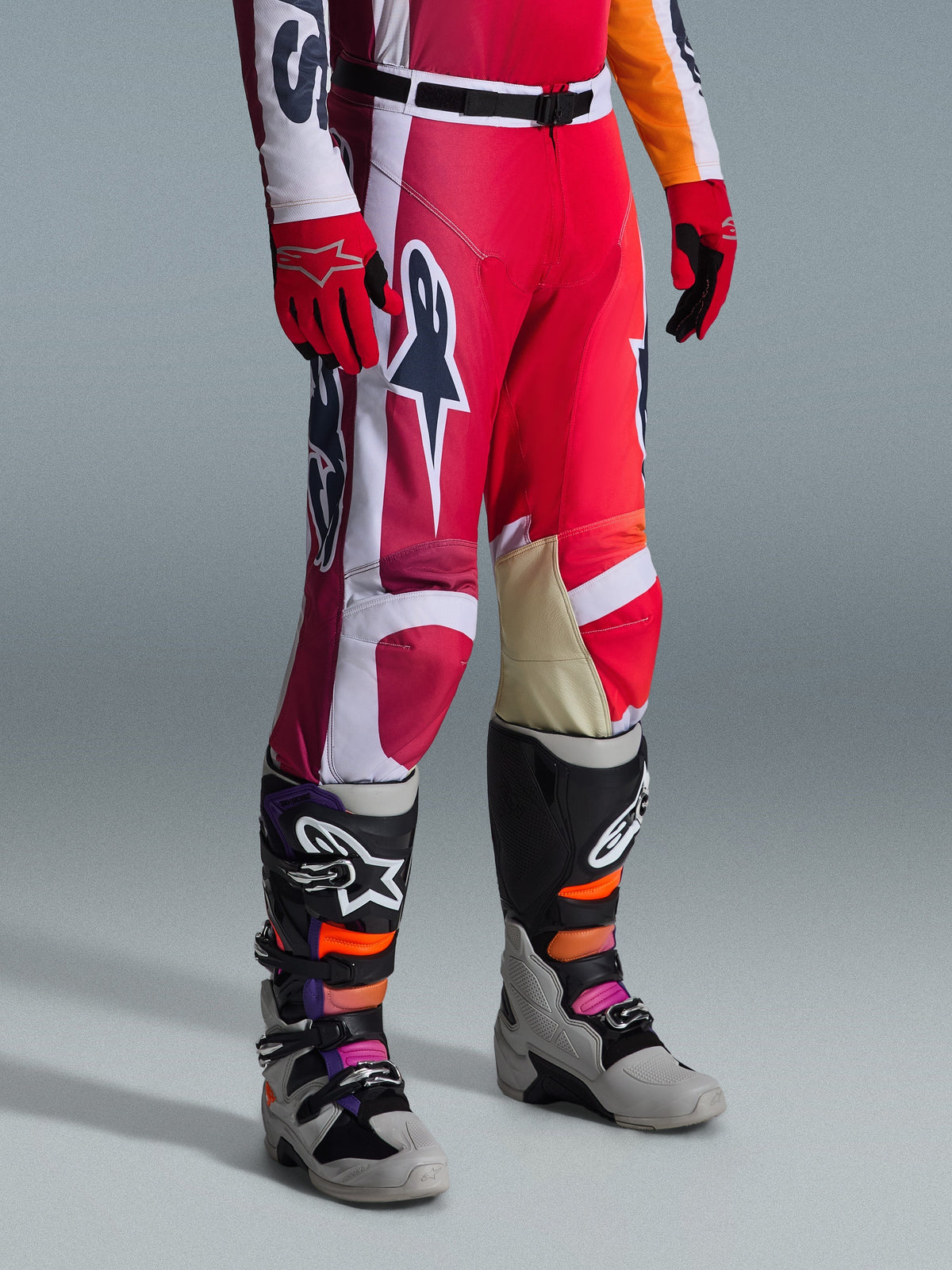 Alpinestars Racer Portl broek 2026, motorcrossbroek, rood, lichtgrijs en donkergrijs, gedragen met bijpassende rode handschoenen en veelkleurige motorcrosslaarzen, voorzien van opvallende Alpinestars-logo's en verstevigde panelen voor off-road racen.