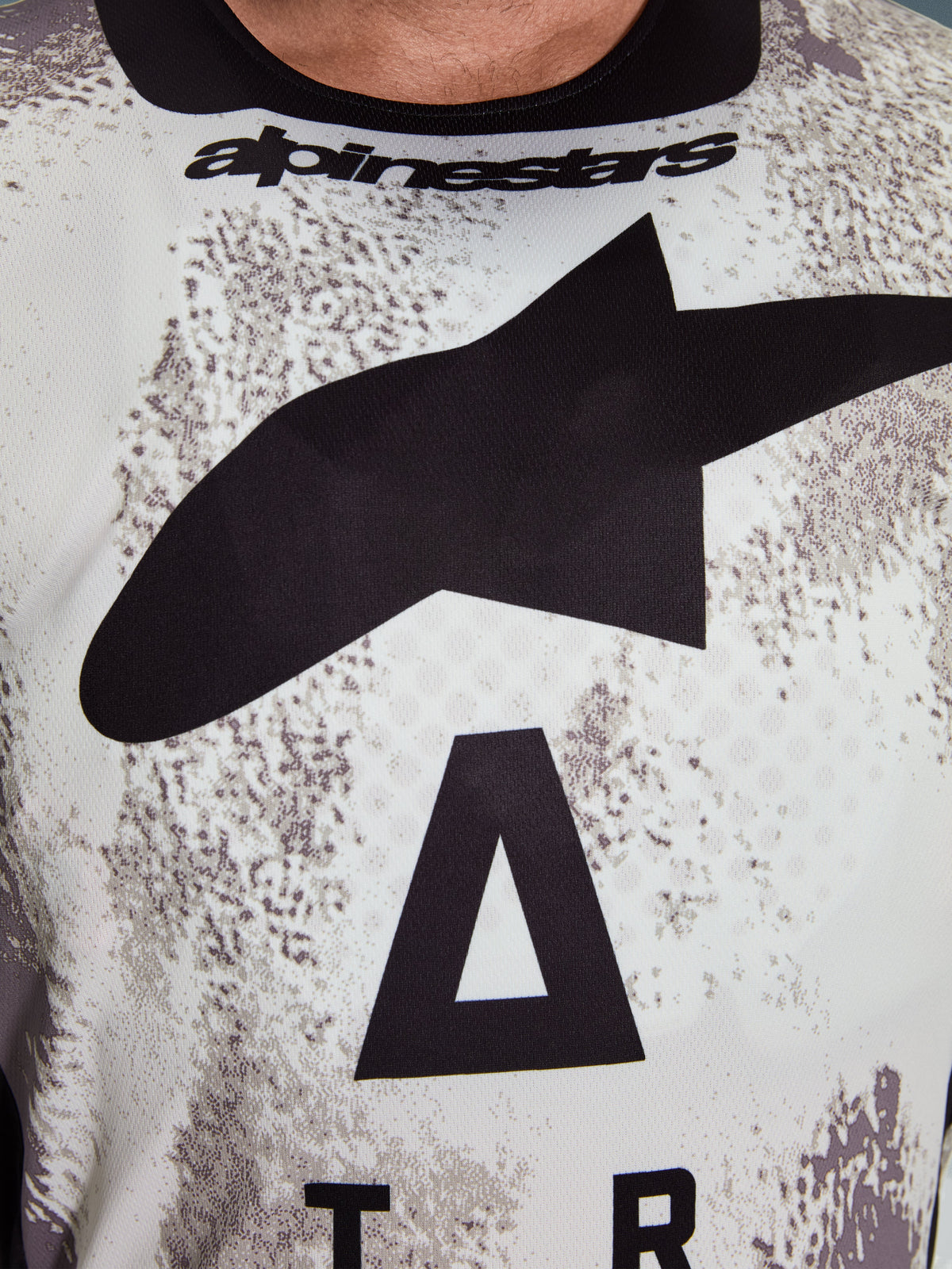 Alpinestars 2026 Racer Lahnd Jersey, motorcross jersey, wit en grijs gespikkeld patroon, close-up van de borst met groot zwart Astars-logo en Alpinestars-branding op de halslijn, prestatiegericht ontwerp voor off-road rijden