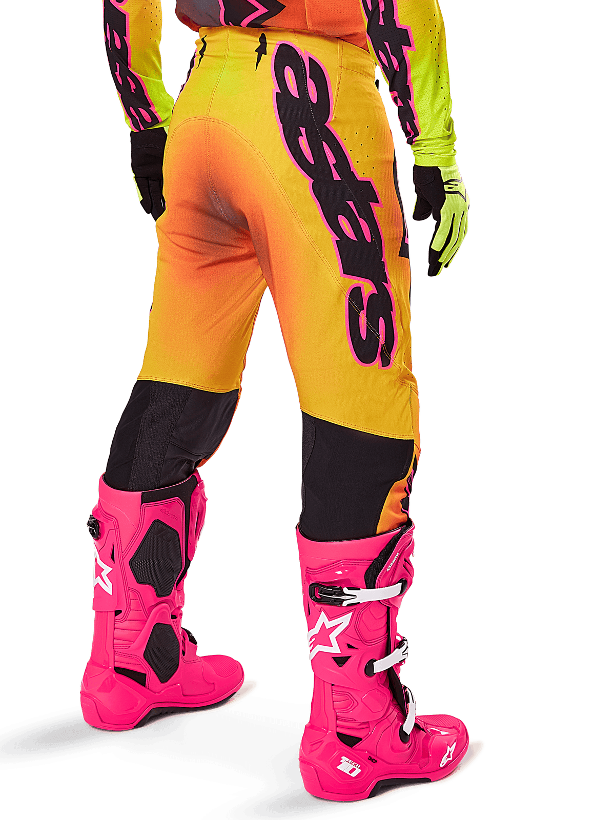 Alpinestars 2025 Supertech Lipan Gear Set, achteraanzicht van motorcrossbroek met geel en oranje kleurverloop en opvallende zwarte branding, gecombineerd met felroze Tech 10 laarzen en gele handschoenen, professionele off-road race-uitrusting