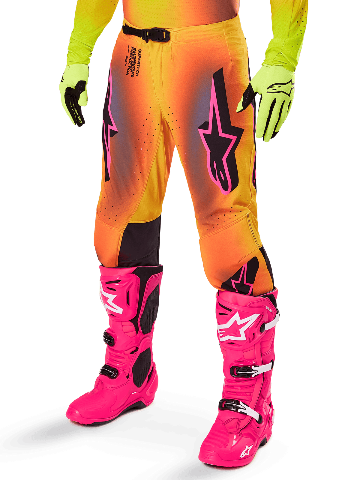 Alpinestars 2025 Supertech Lipan Gear Set, motorcrossbroek, geel en oranje kleurverloop met roze en paarse accenten, zwarte logo's op de dijen, gedragen met gele handschoenen en felroze motorcrosslaarzen