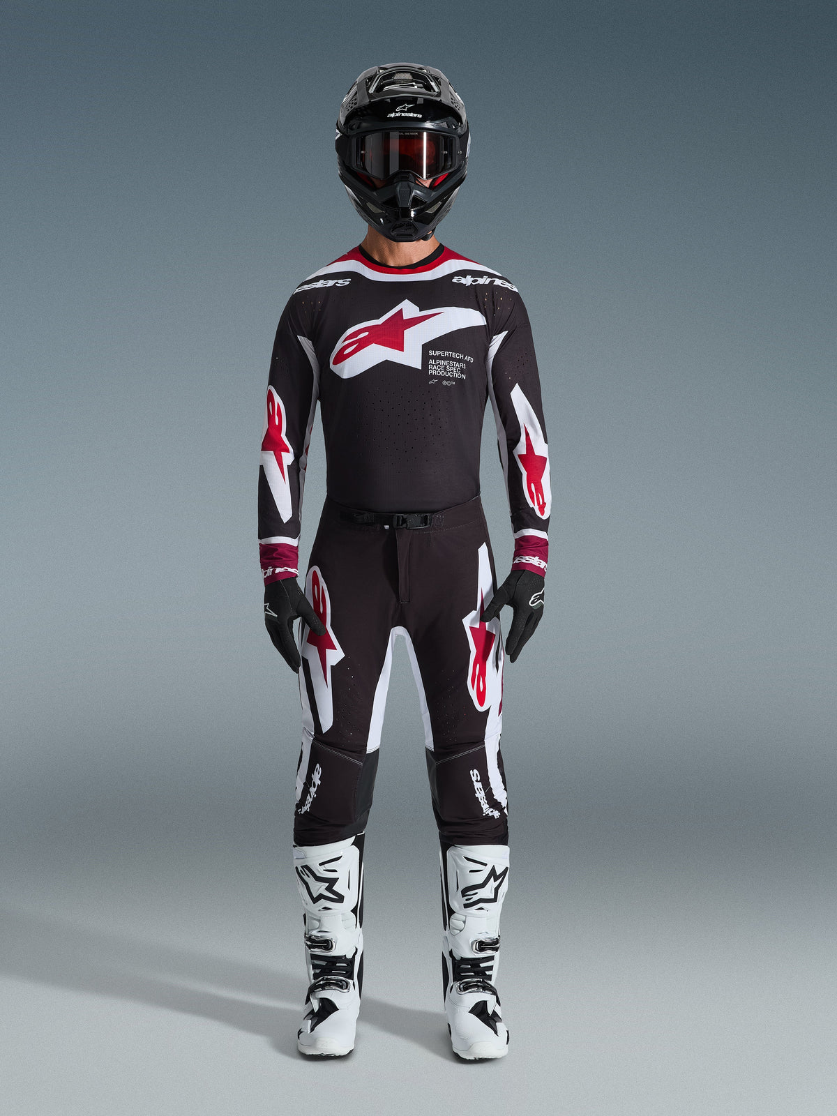 Alpinestars 2026 Supertech AFD Vista Gear Set, motorcross race-uitrusting, zwart met rode en witte accenten, volledige outfit inclusief jersey en broek met sterlogo, zwarte helm en witte laarzen, professionele MX-kleding voor off-road prestaties