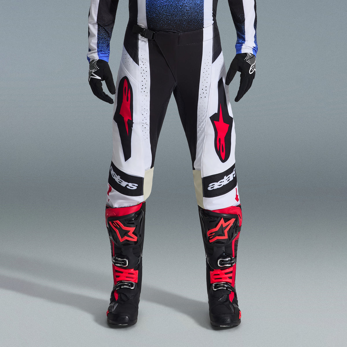 Alpinestars 2026 Techstar Knif Gear Set, motorcrossuitrusting, zwart-witte broek met grote rode sterlogo's, gedragen met zwart-rode racelaarzen en zwarte handschoenen, professionele atletische pasvorm voor off-road prestaties