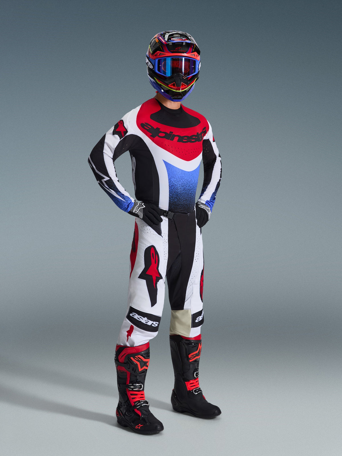 Alpinestars 2026 Techstar Knif broek, motorcross broek, zwart, wit en rood, gedragen door een rijder in volledige race-uitrusting met bijpassende jersey en laarzen, voorzien van opvallende rode Alpinestars-logo's op witte panelen en een prestatiegerichte atletische pasvorm.