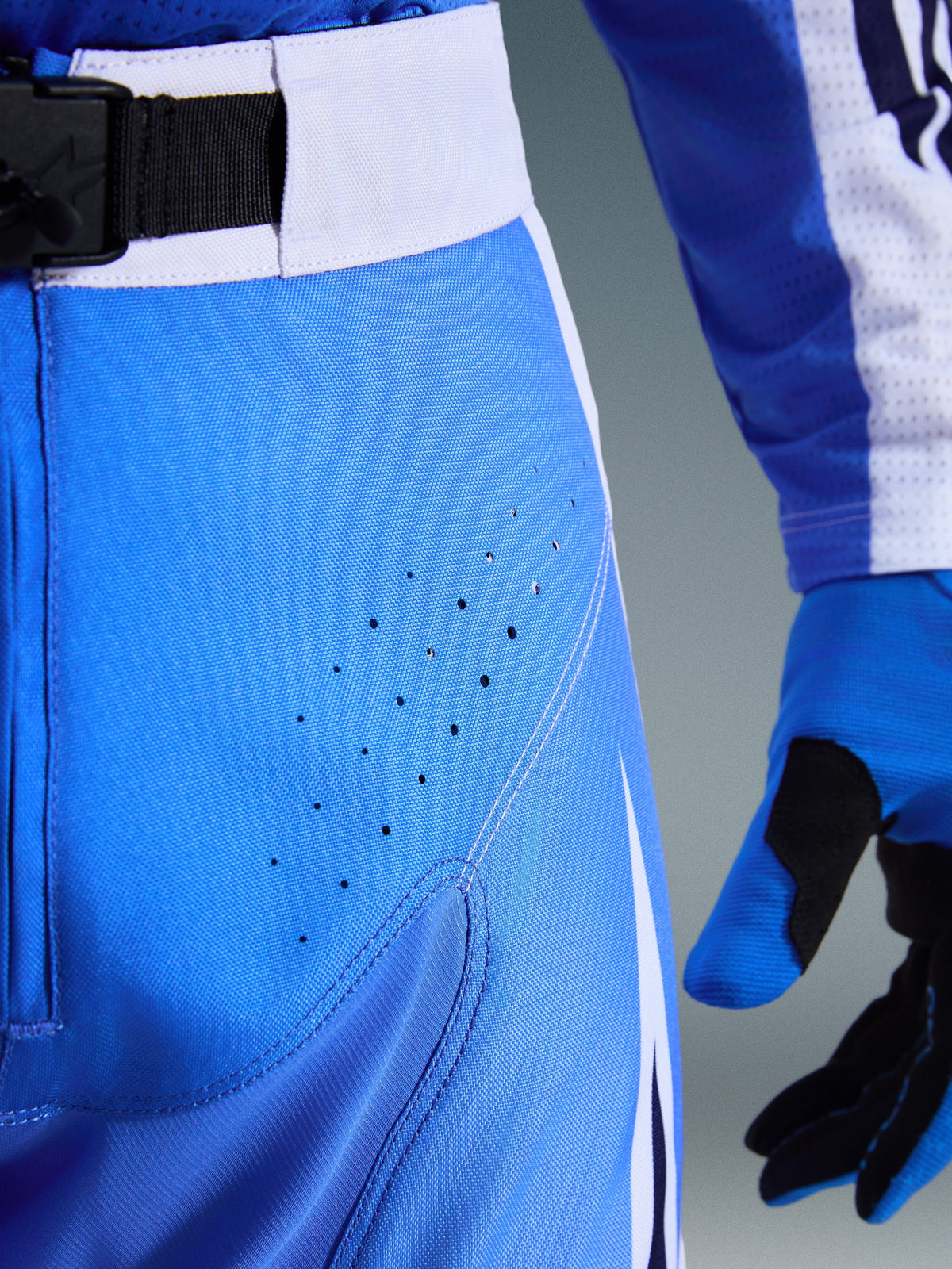 Alpinestars 2026 Techstar Knif broek, motorcrossbroek, Ucla blauw en zwart, detailopname van de dij met lasergesneden perforaties en SX2 magnetische taillesluiting, technische constructie voor off-road racing
