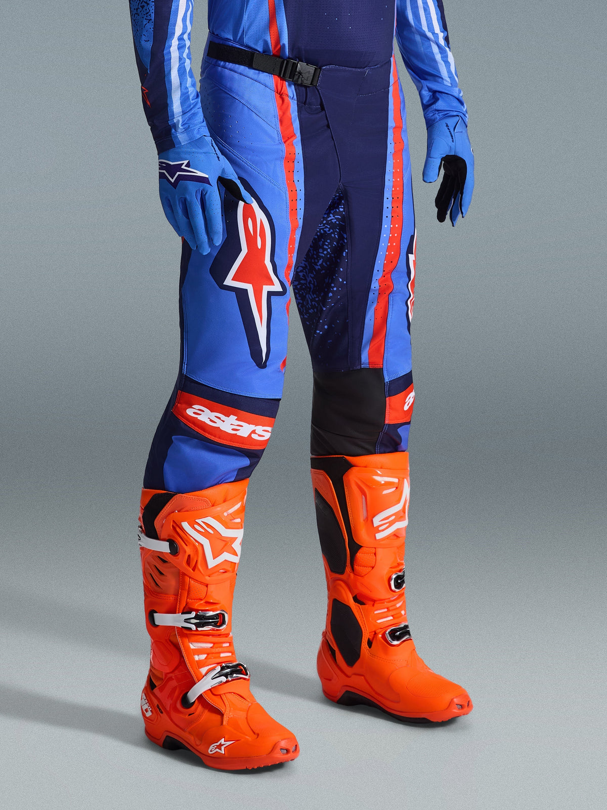Alpinestars 2026 Techstar Nomur Pants, Motocross Pants, Dark Navy Orange and UCLA Blue, worn with bright orange motocross boots and matching blue gear, featuring bold branding and multi-material construction for off-road performance.