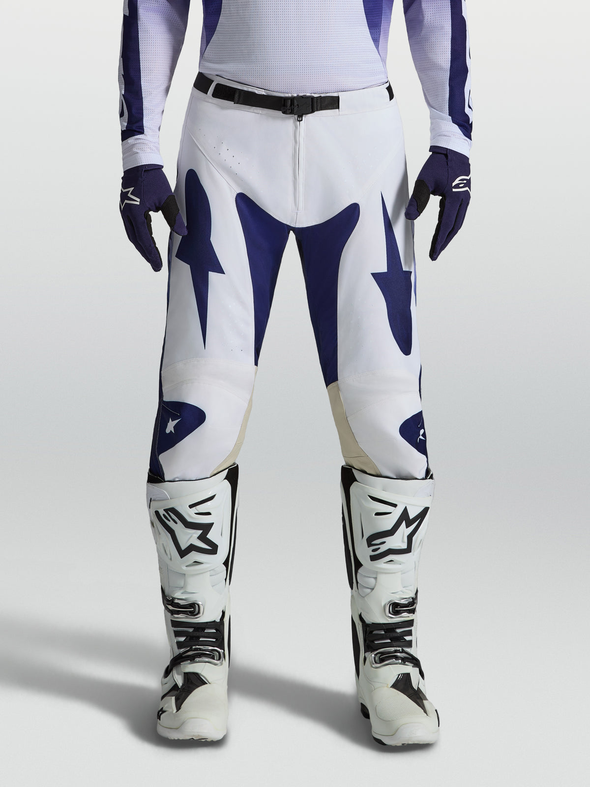 Alpinestars Racer Air Amber broek, geperforeerde blauwe en witte motocrossbroek voor high-performance off-road rijden, gedragen door een model met bijpassende jersey en laarzen.