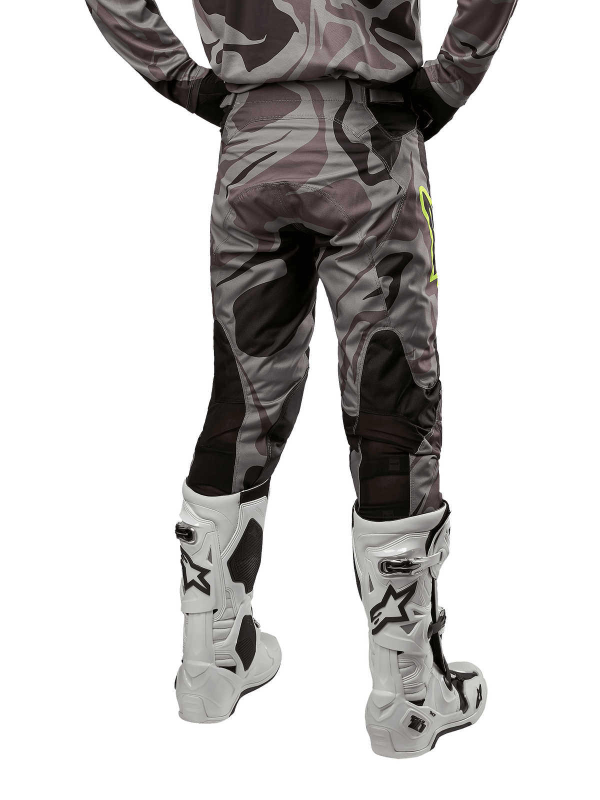 Alpinestars 2024 Racer Tactical broek, motorcrossbroek, Cast Gray Camo Magnet, achteraanzicht met camouflagepatroon en zwarte ademende stretchzones, gedragen met witte en zwarte motorcrosslaarzen, ontworpen voor off-road racen.