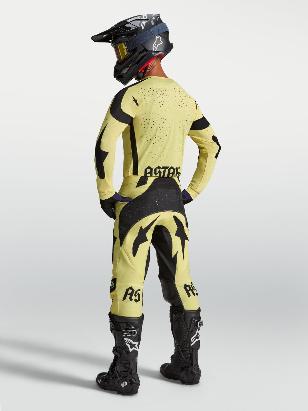 Alpinestars Techstar Atrox broek en gear set, geel en zwarte motocross-outfit, achteraanzicht op model met motorlaarzen.