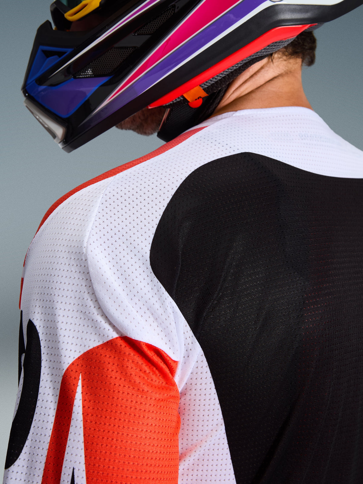 Alpinestars 2026 Racer Air Portl Jersey, motocross shirt, multicolor met witte, zwarte en rode panelen, close-up van de geperforeerde mesh-constructie op de schouder en rug voor ventilatie, gedragen met een kleurrijke motocrosshelm